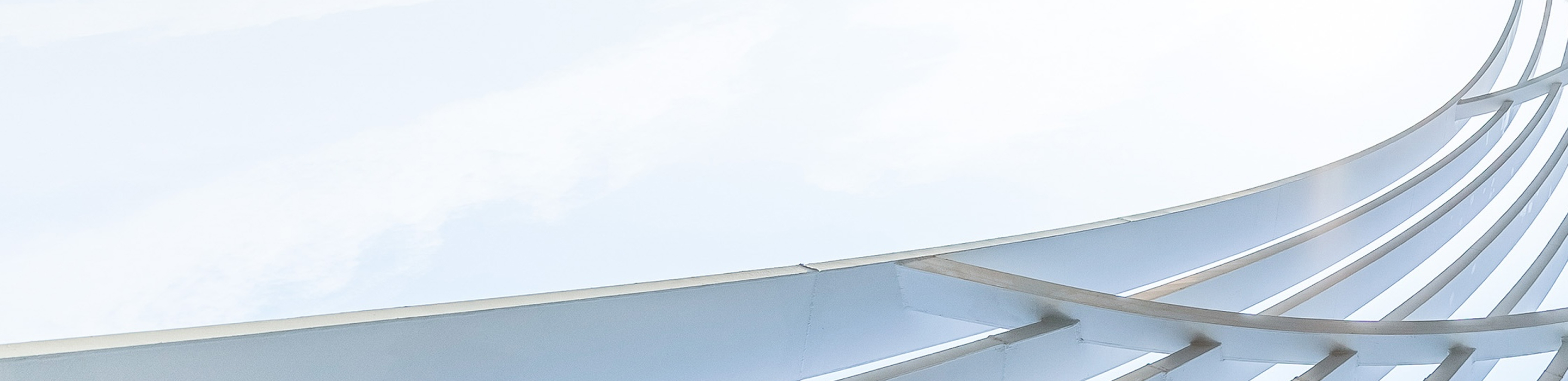Abstract architectural detail of curved white beams and structural elements against sky.