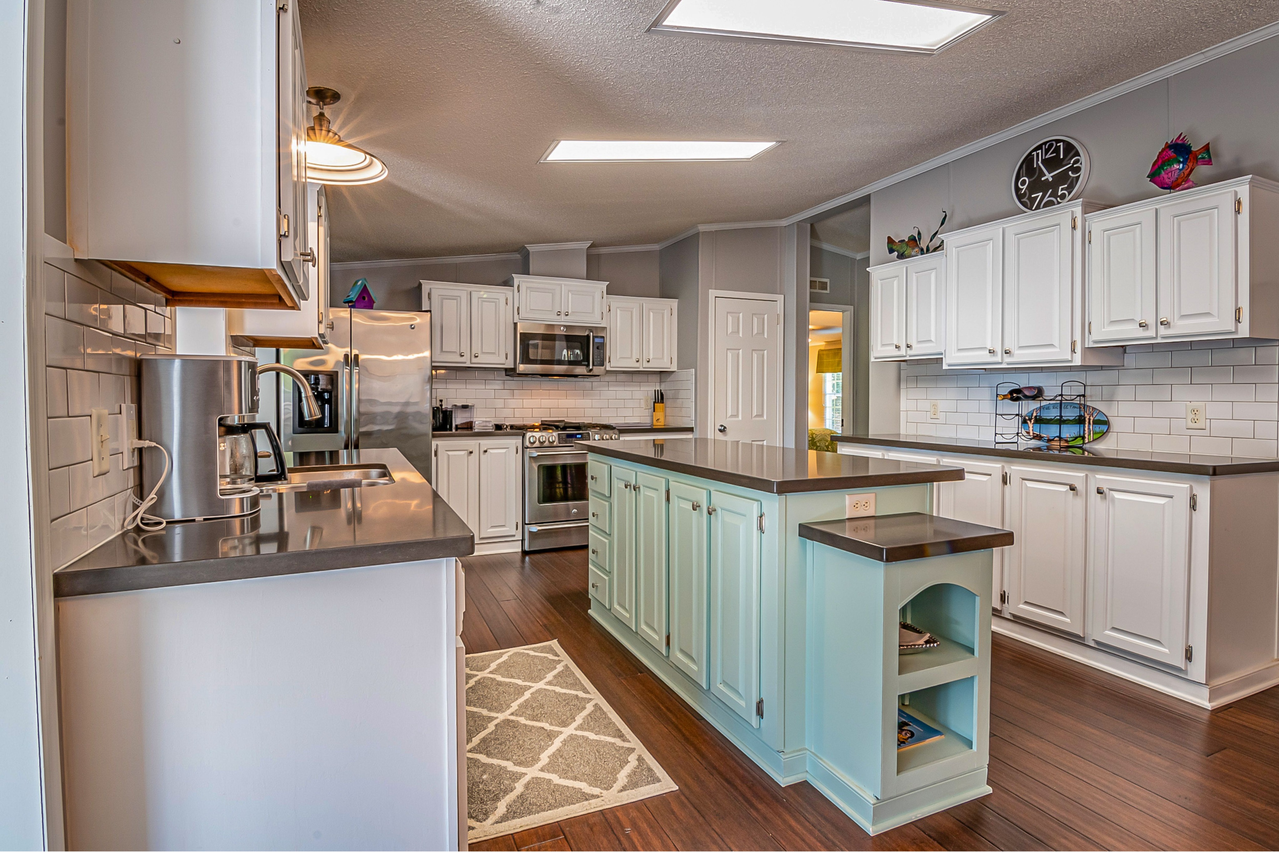 Kitchen showcasing white perimeter cabinets with a contrasting light blue island for a fresh, customized look. This image represents Crest & Crown LLC’s cabinet painting services, including modern color updates and detailed finishes.