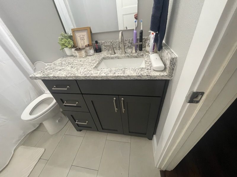 Compact bathroom remodel featuring dark cabinetry, granite countertop, undermount sink, modern hardw 