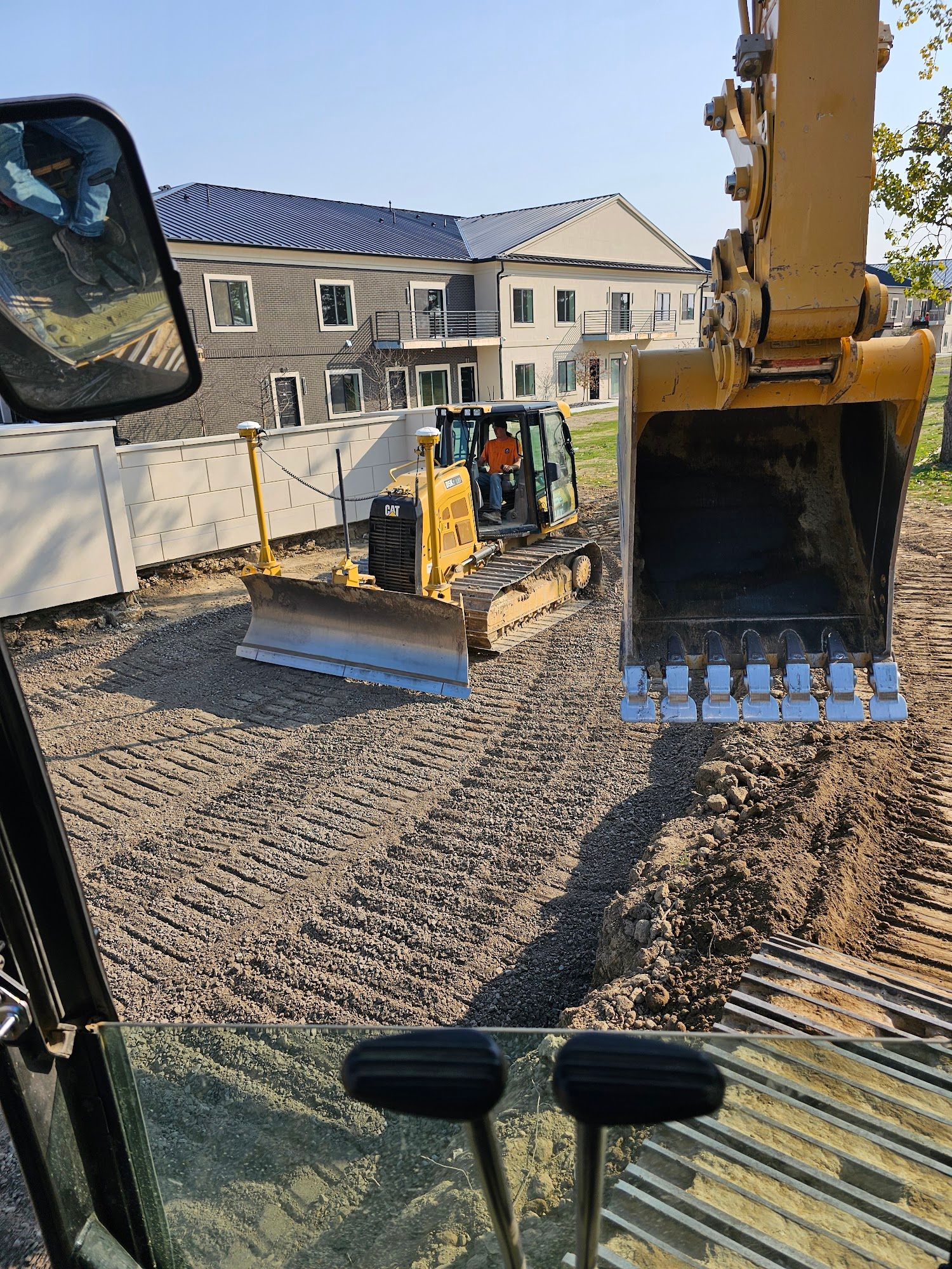 Heavy construction equipment performs grading and surface preparation on a residential development project. Operators shape the site to achieve required elevations and drainage performance.