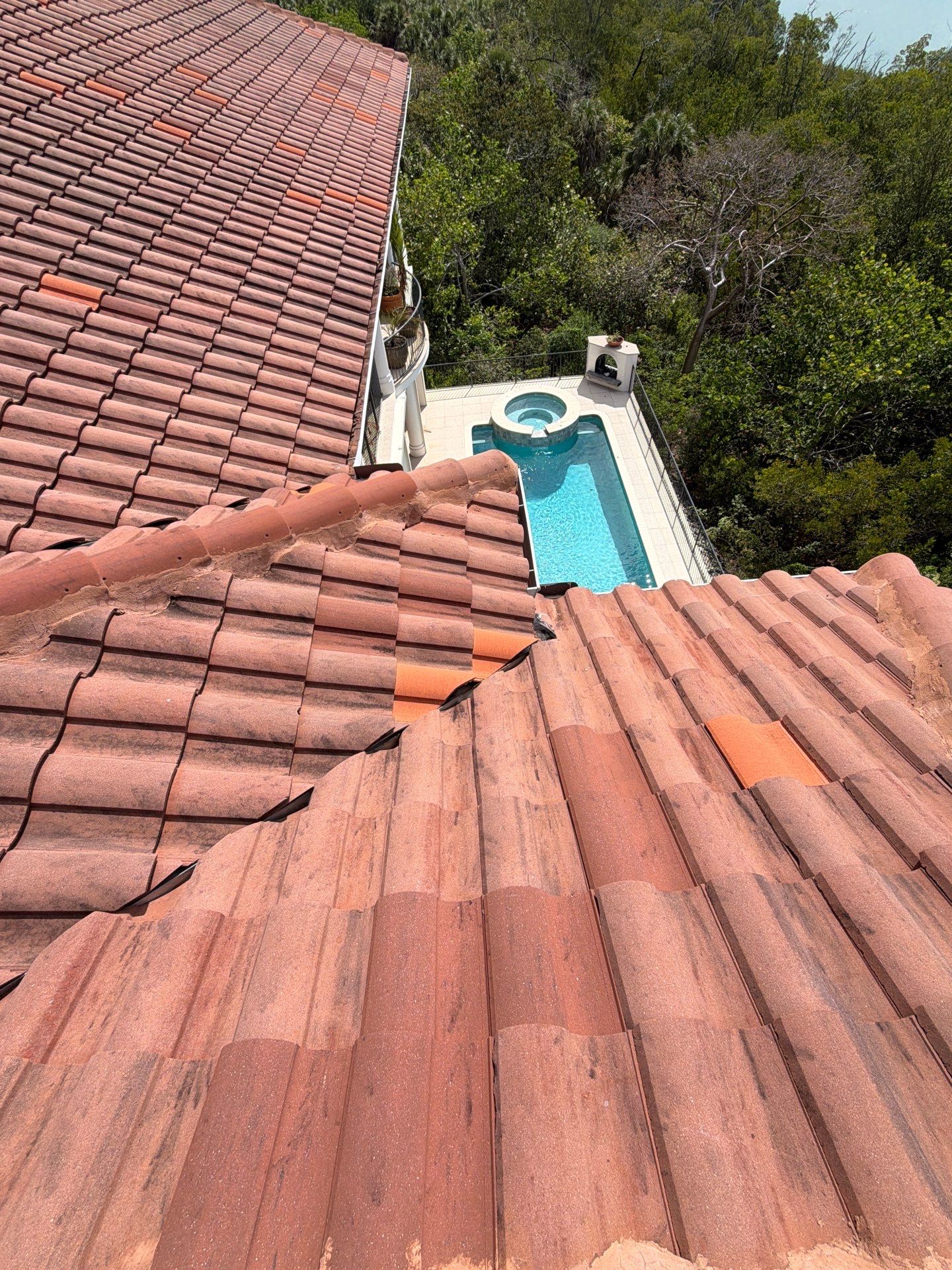 Close-up view of a clay tile roof with a small section opened for repair, showing underlayment work  