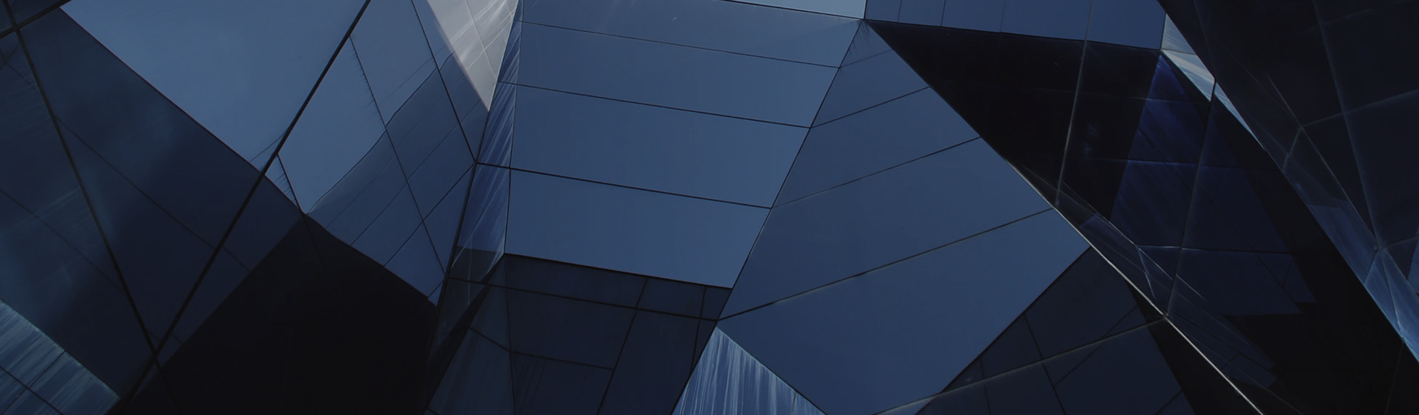 Close-up and abstract image of a modern, angular, glass-faced building.