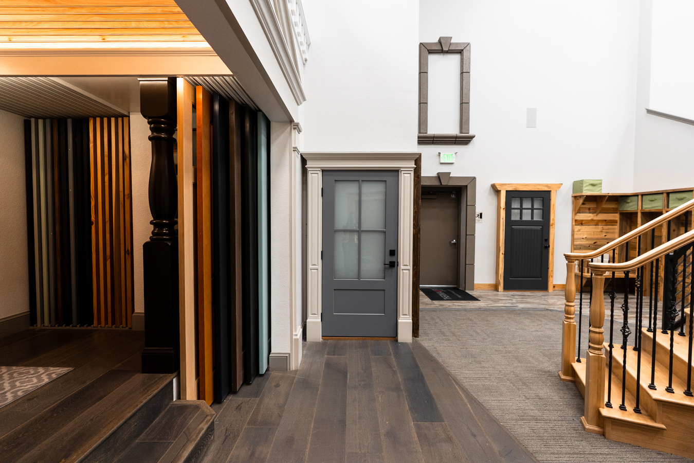 Builders FirstSource showroom with diverse doors, wood finishes, and elegant staircase, showcasing construction materials.