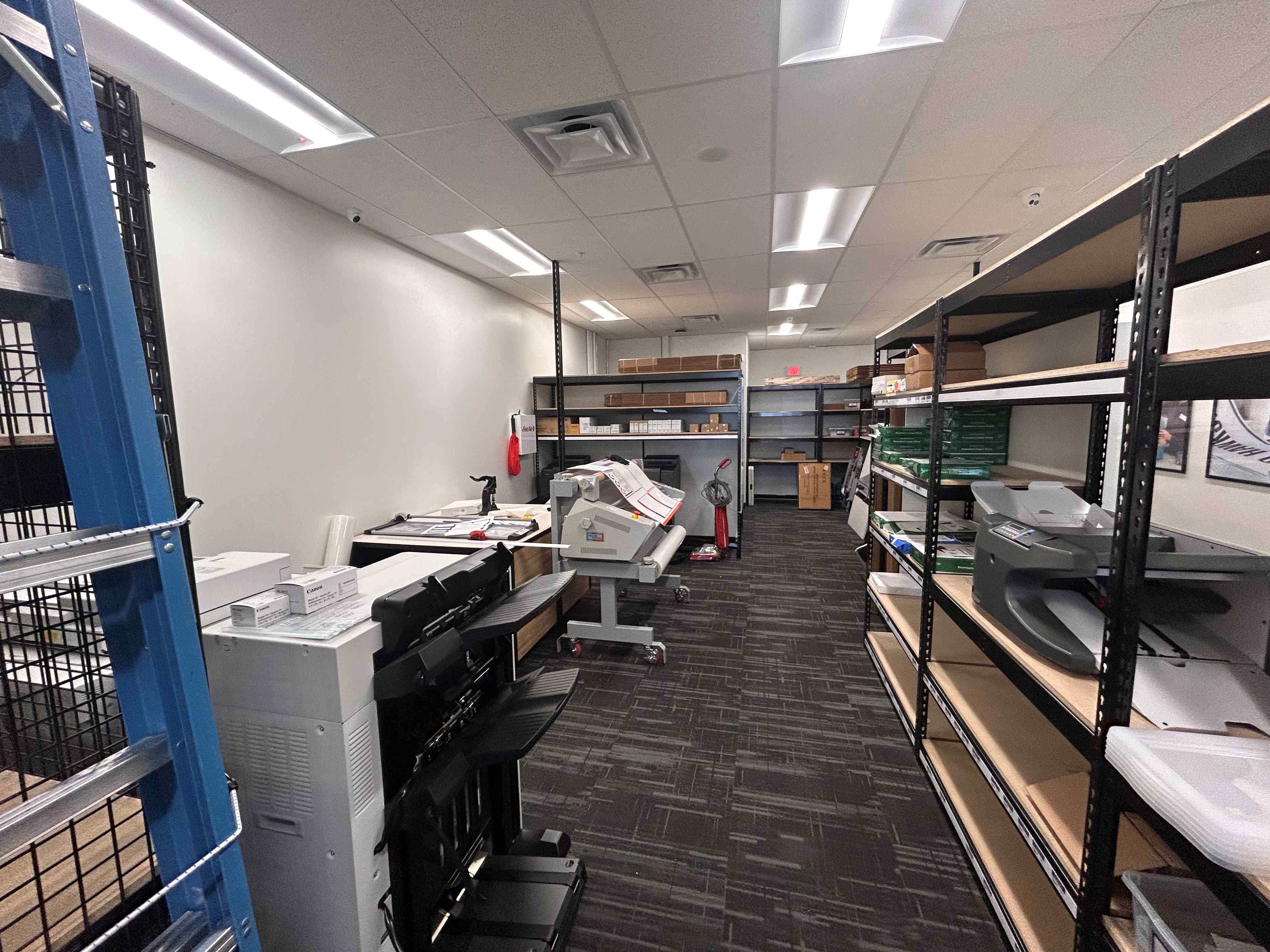 A view of the back-of-house print production area, including large-format equipment and supply shelv 
