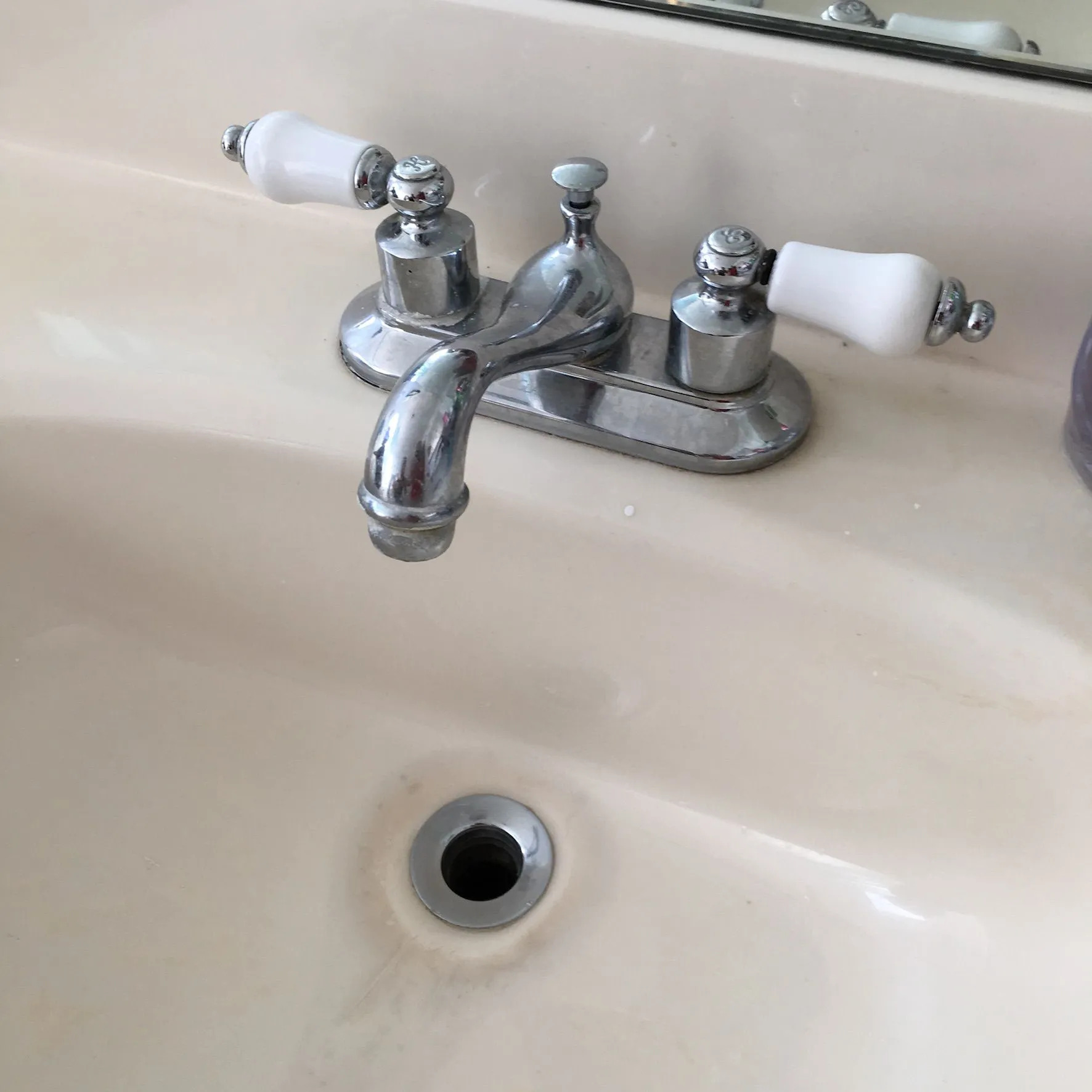 Bathroom sink featuring a polished chrome faucet with white handles installed on a durable vanity, h 