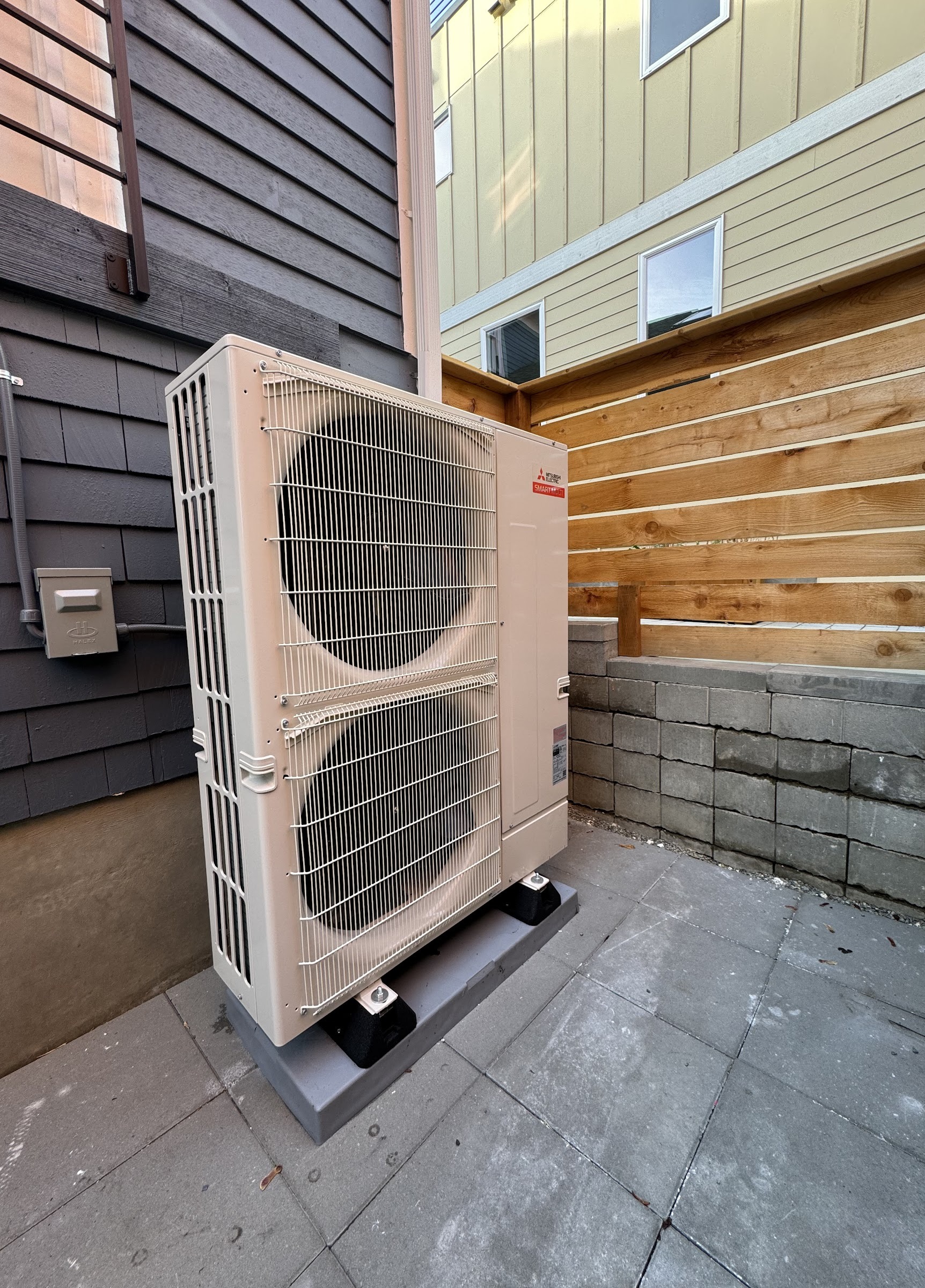 Mitsubishi Hyper-Heat dual-fan heat pump installed in a narrow side yard. Cold-climate heat pump installation by Ready Energy Solutions.