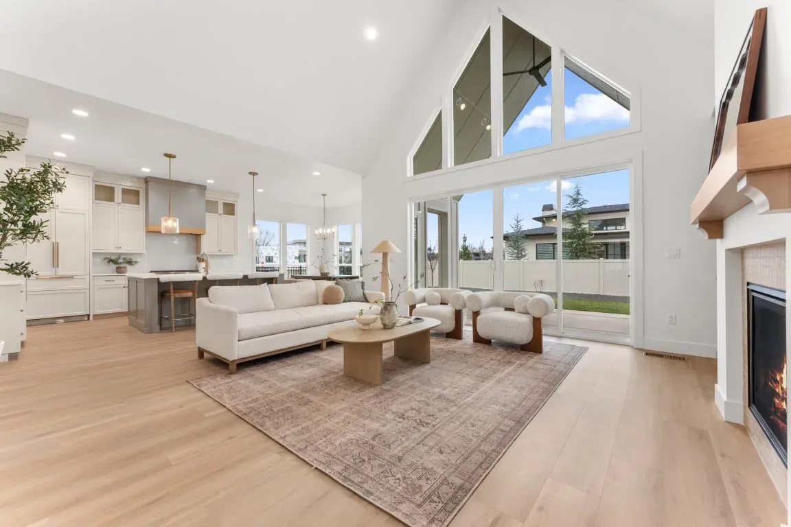 The open living space showcases premium flooring, soaring ceilings, custom ceiling treatments, and a dramatic 48-inch Napoleon gas fireplace.