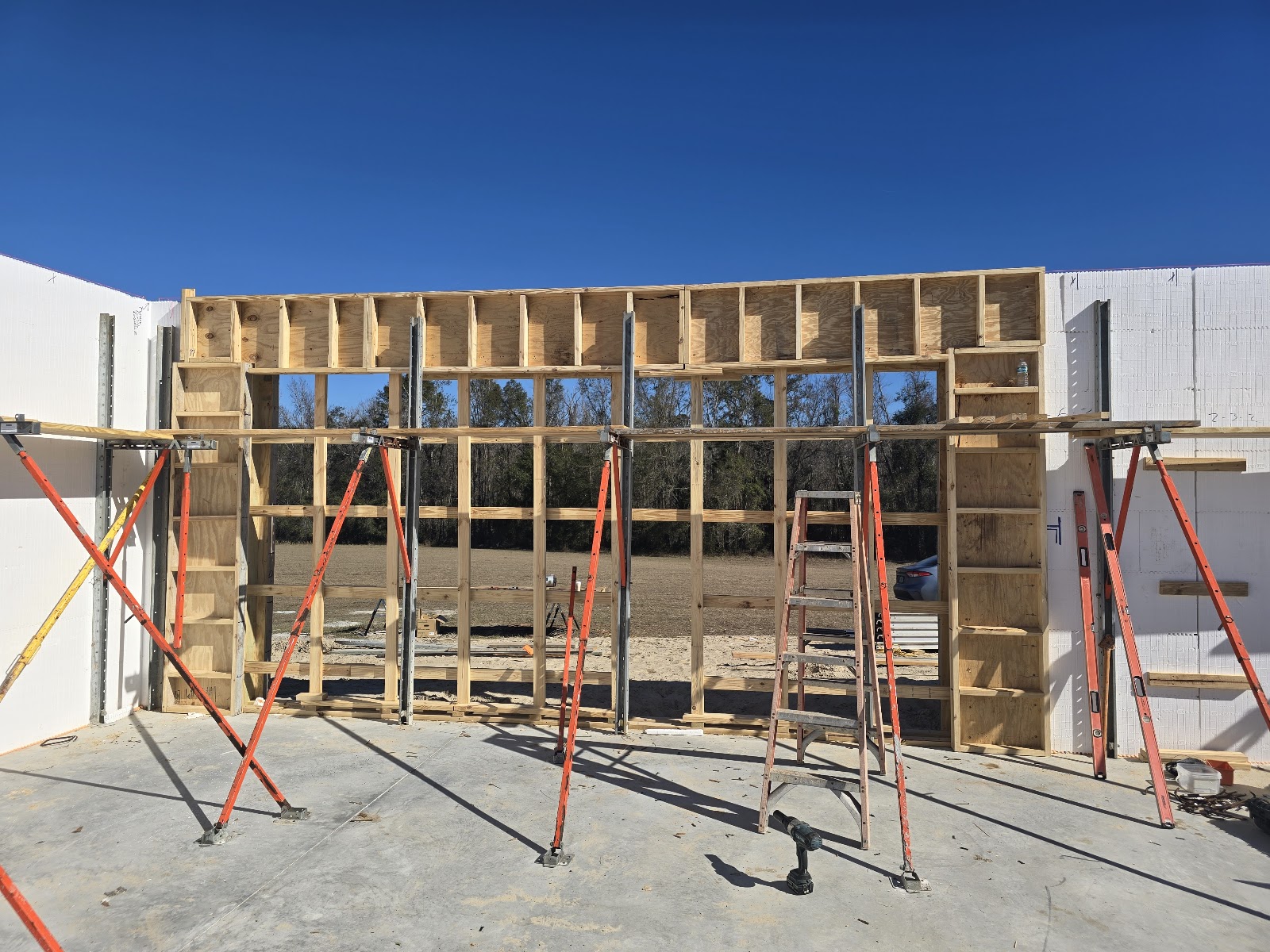 A construction site with a wooden frame structure being built inside an insulated concrete form (ICF 