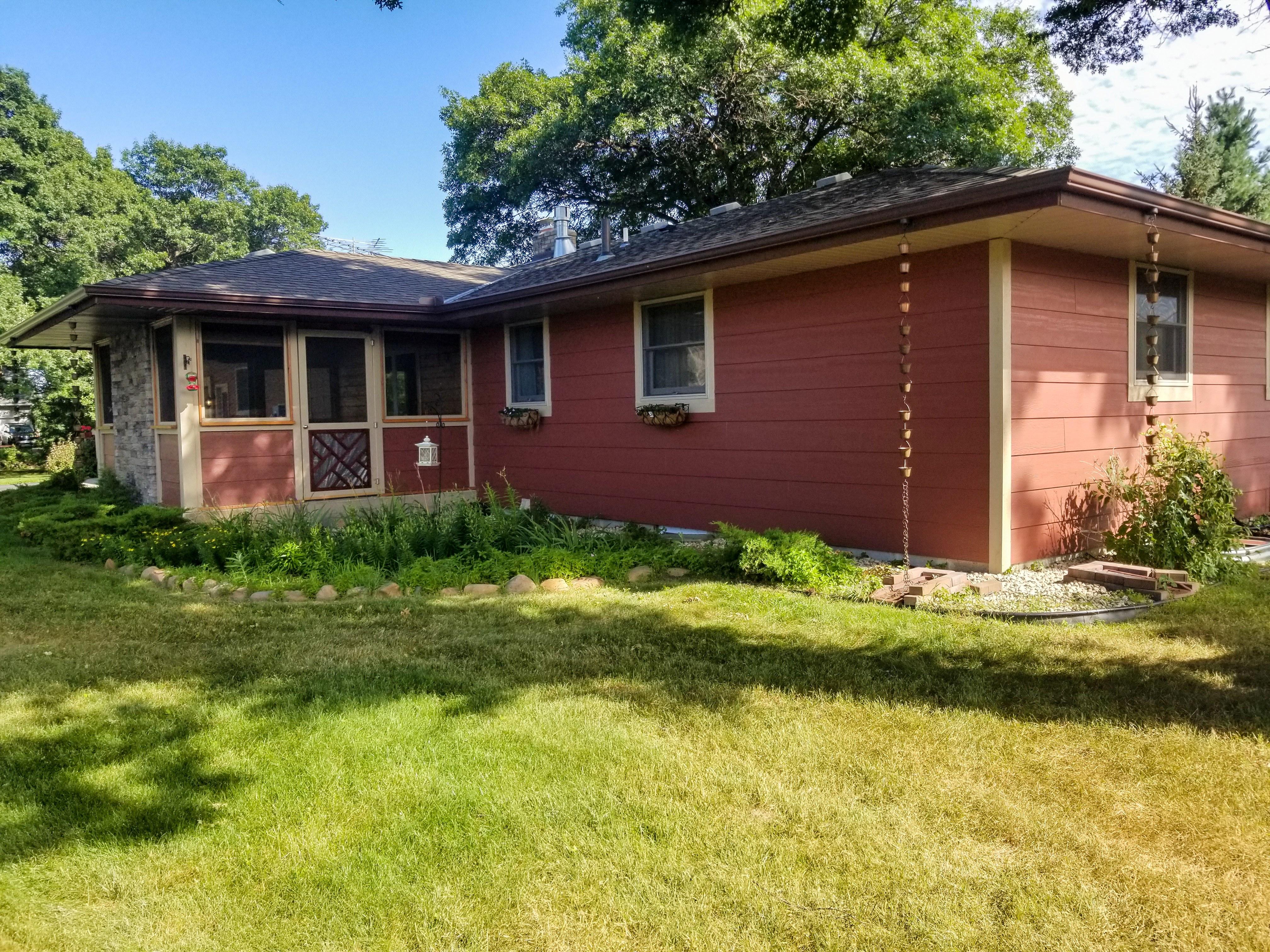 Dark brown seamless gutters featuring multiple decorative rain chains installed on a single-story red home by Ultimate Gutter Solutions.