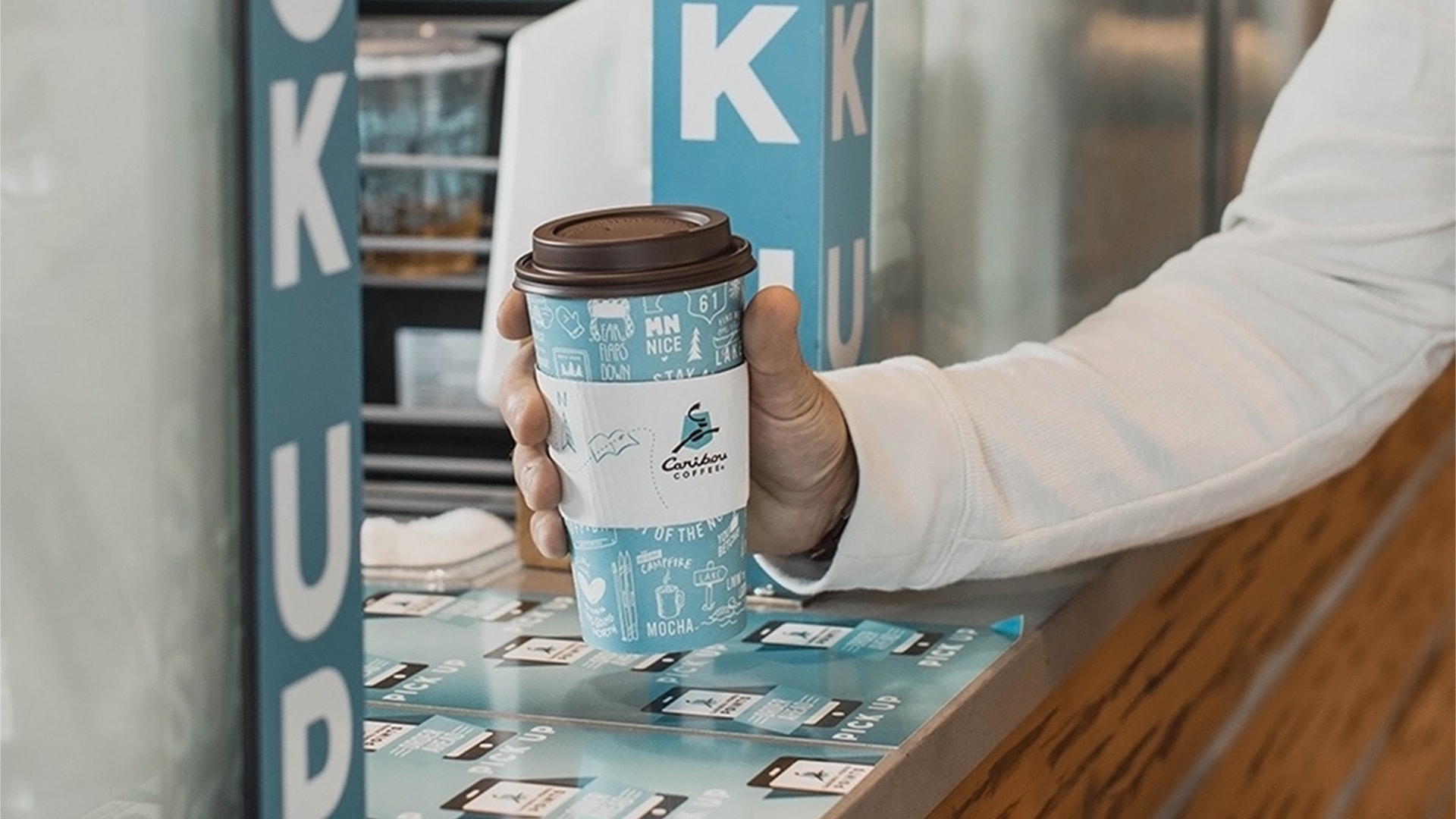 A customer grabs a cup of Caribou Coffee.