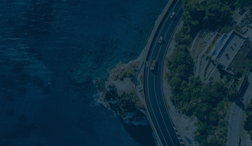 Top-down view of cars driving along a curved lakeside road.