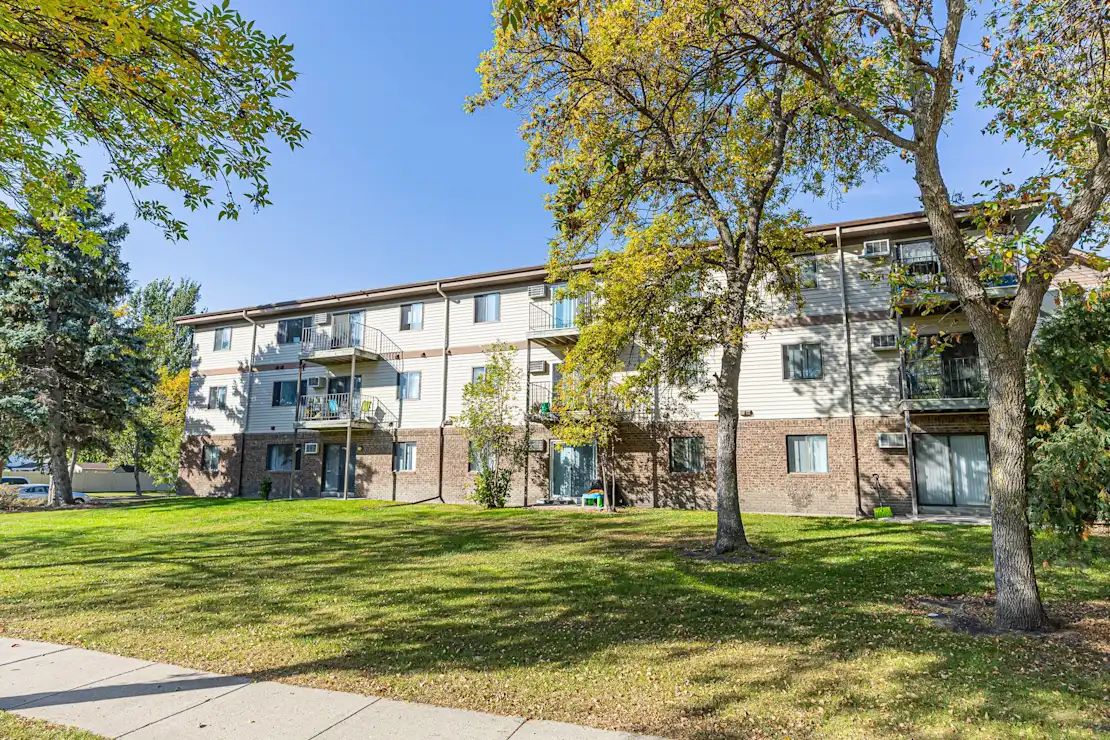 A tree with yellow leaves is in front of a building, Pine Pointe Apartments, Fargo, ND.