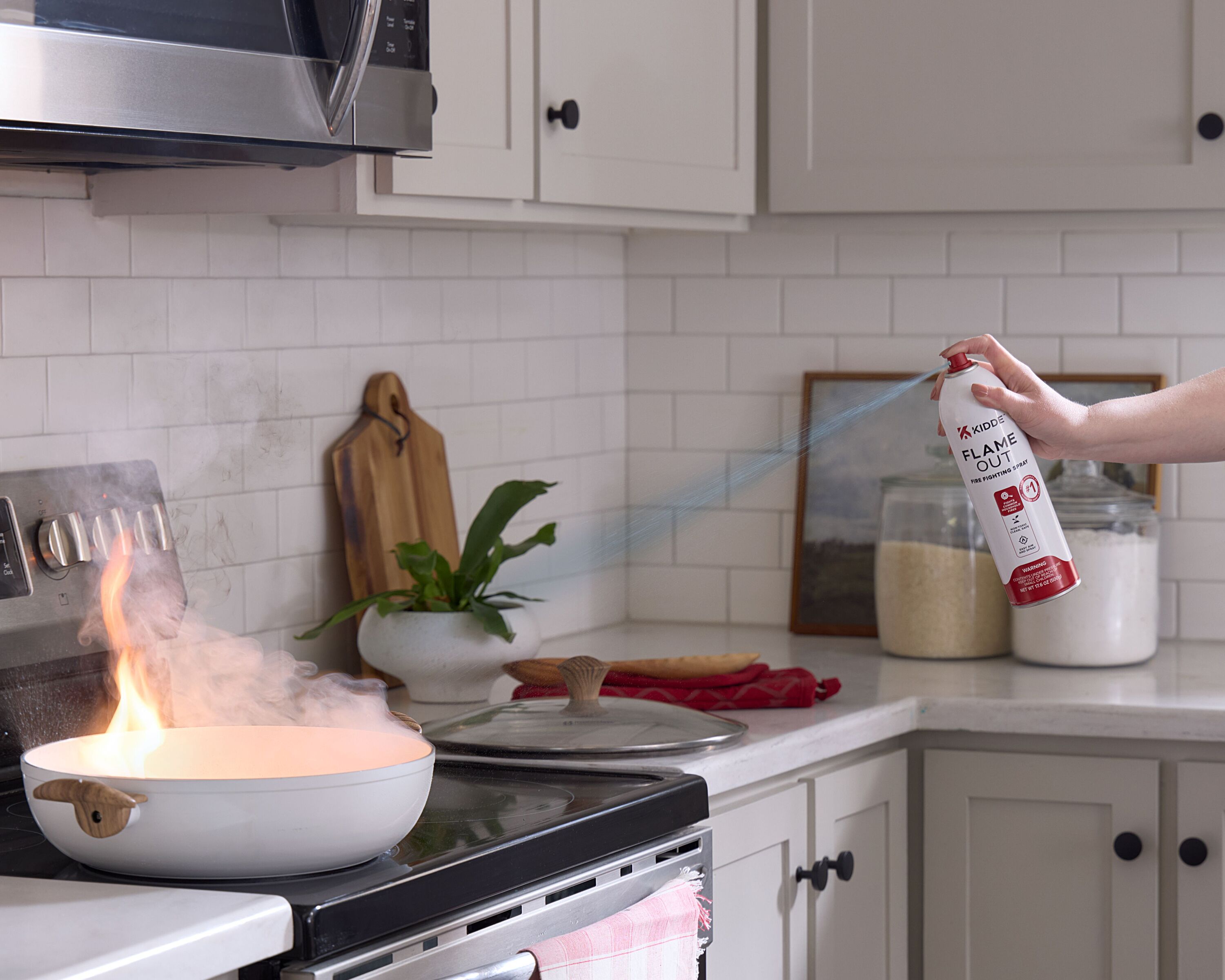 A person uses the Flameout Spray on a fire in a frying pan.