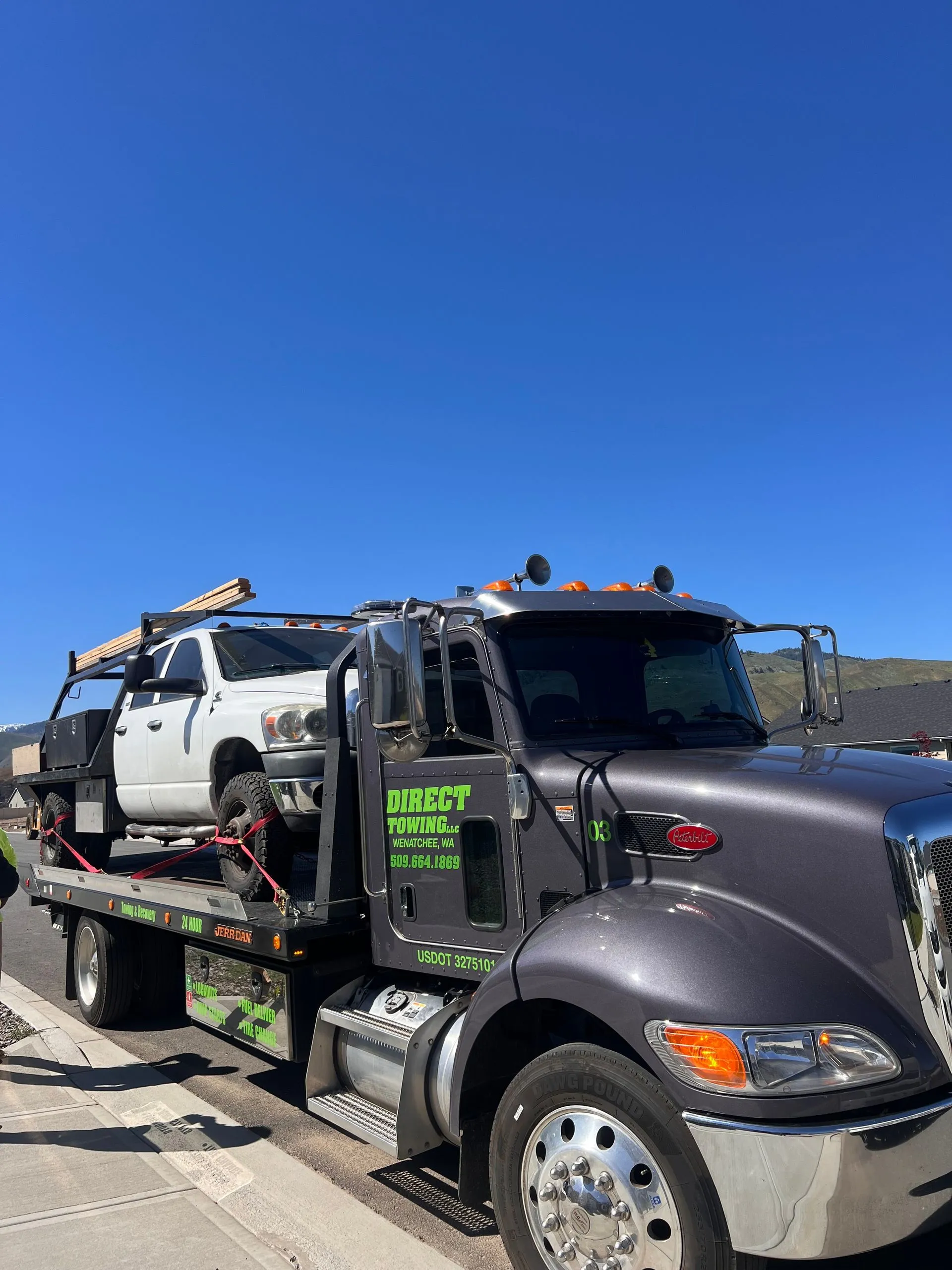 Direct Towing flatbed transporting a work truck equipped with materials and tools, highlighting commercial vehicle towing, safe transportation methods, professional recovery services, and dependable roadside assistance.