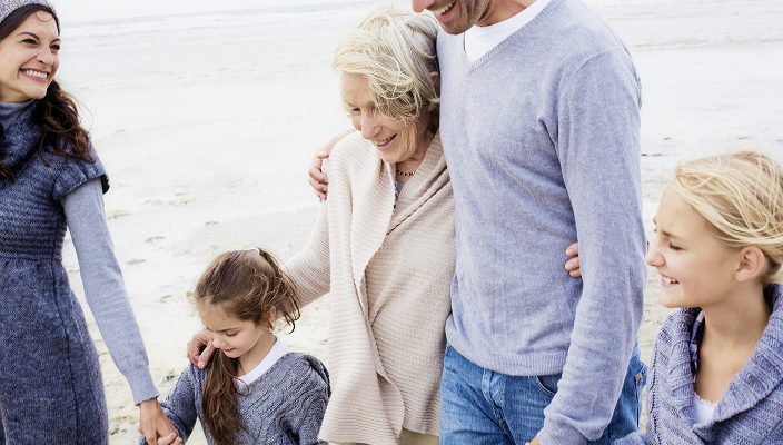 A multigenerational family walking along a beach.