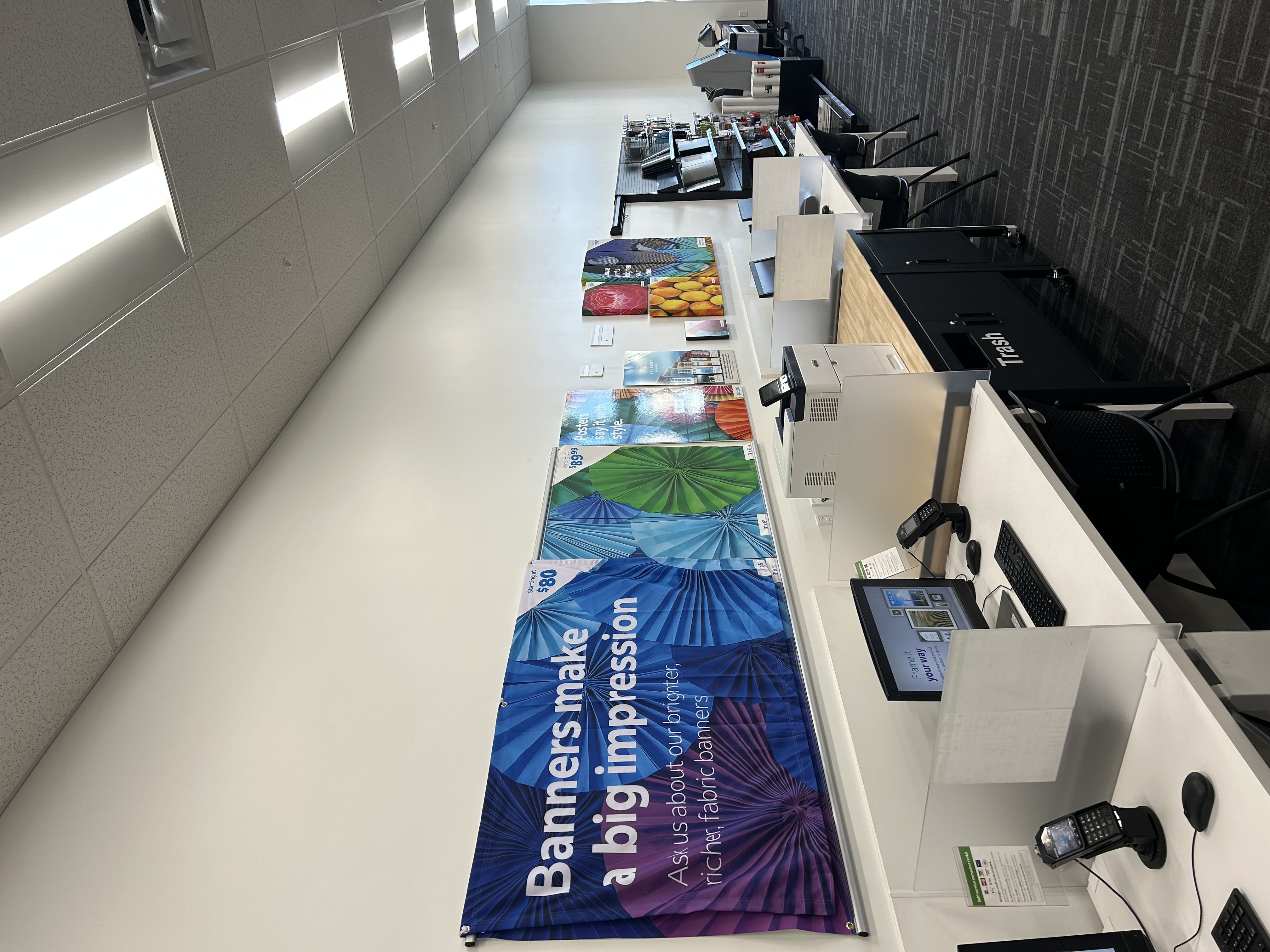 Self-service printing area at FedEx Office North Miami FL with workstations and banner printing examples on display.