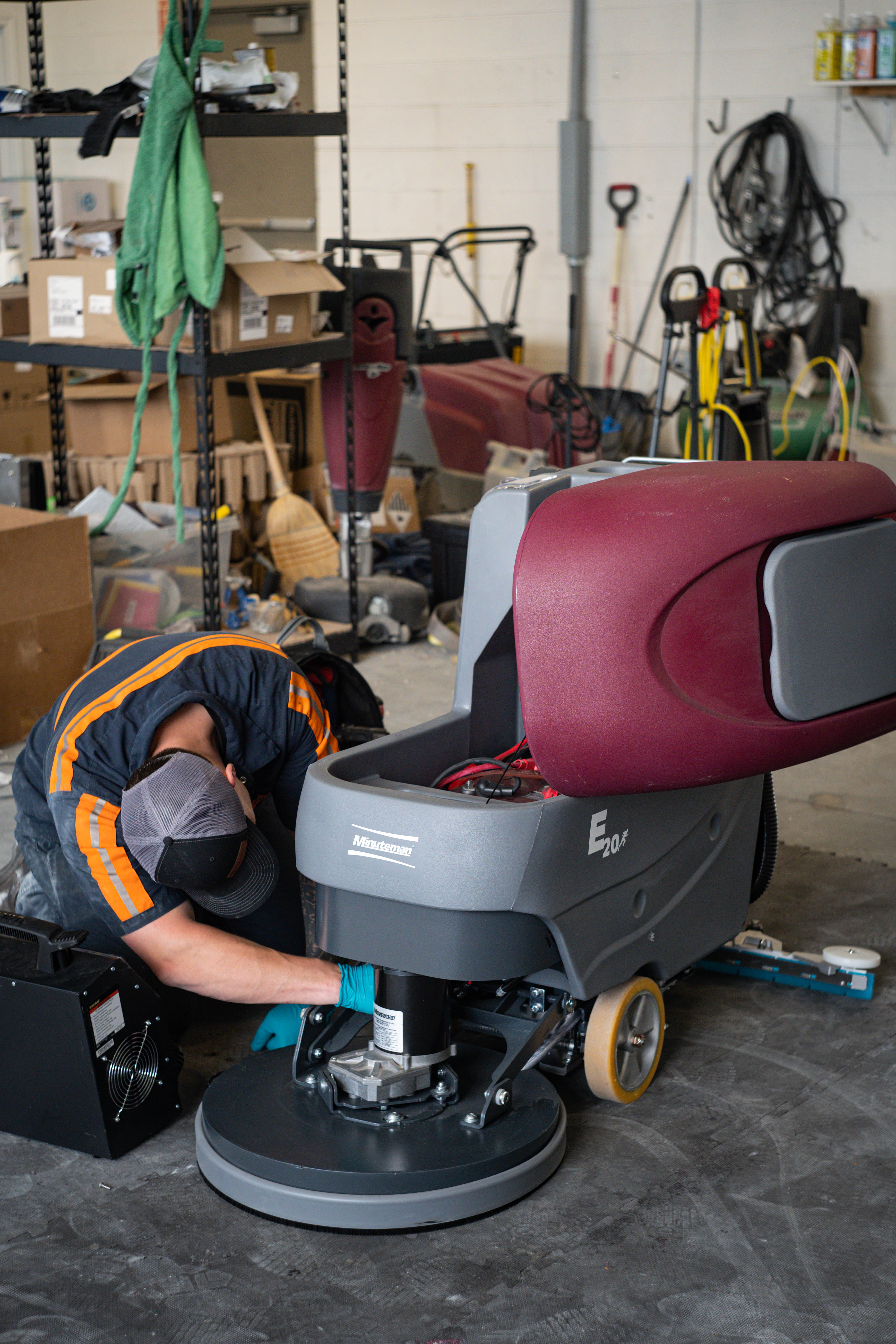 A WaySolutions field technician performs hands-on maintenance on the lower scrub deck and motor assembly of a Minuteman E20 walk-behind floor scrubber. Our local repair services in Layton, Utah, guarantee maximum scrubbing friction and optimal ground-level performance for your heavy-duty commercial equipment.