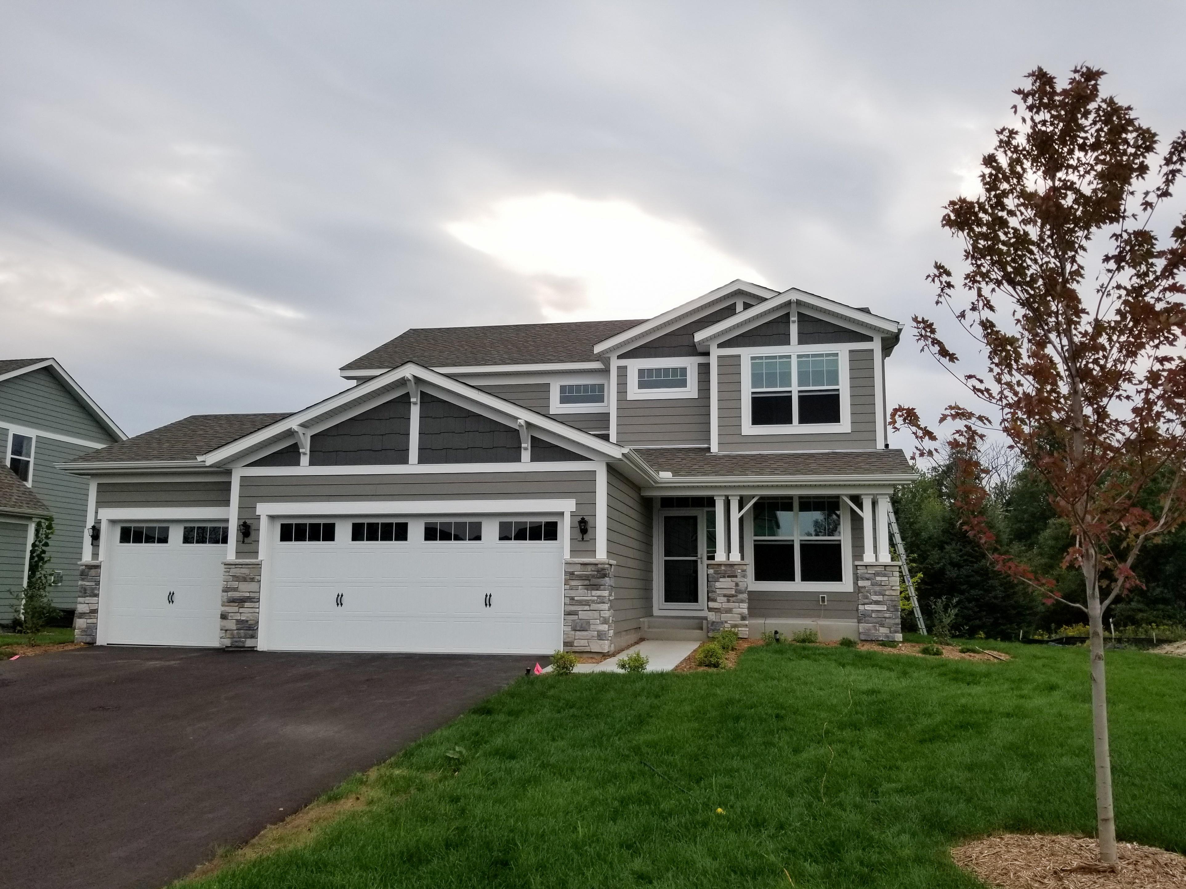 White seamless gutters and downspouts installed on a beautiful modern grey two-story home by Ultimate Gutter Solutions.
