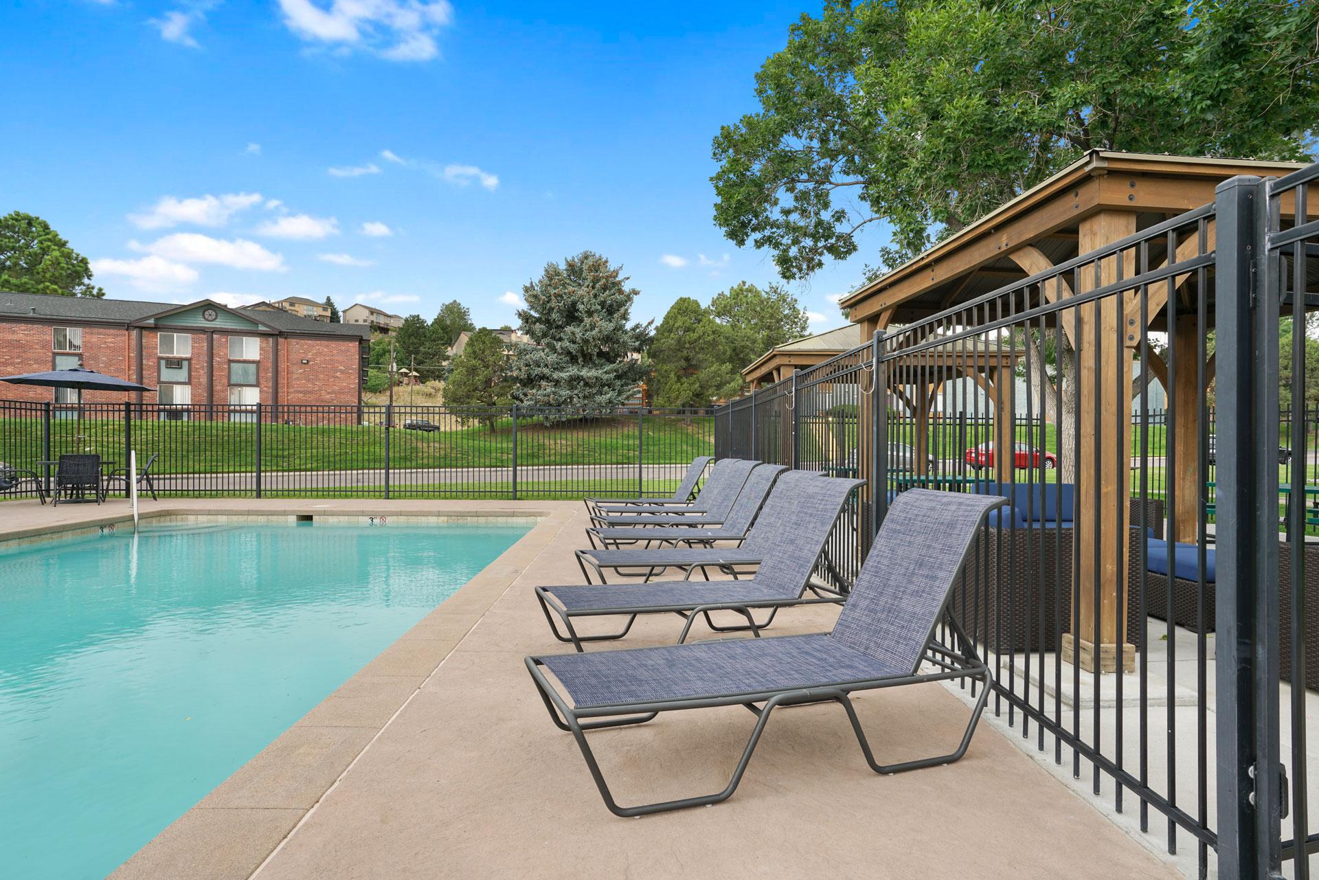 A pool with lounge chairs and a fence.