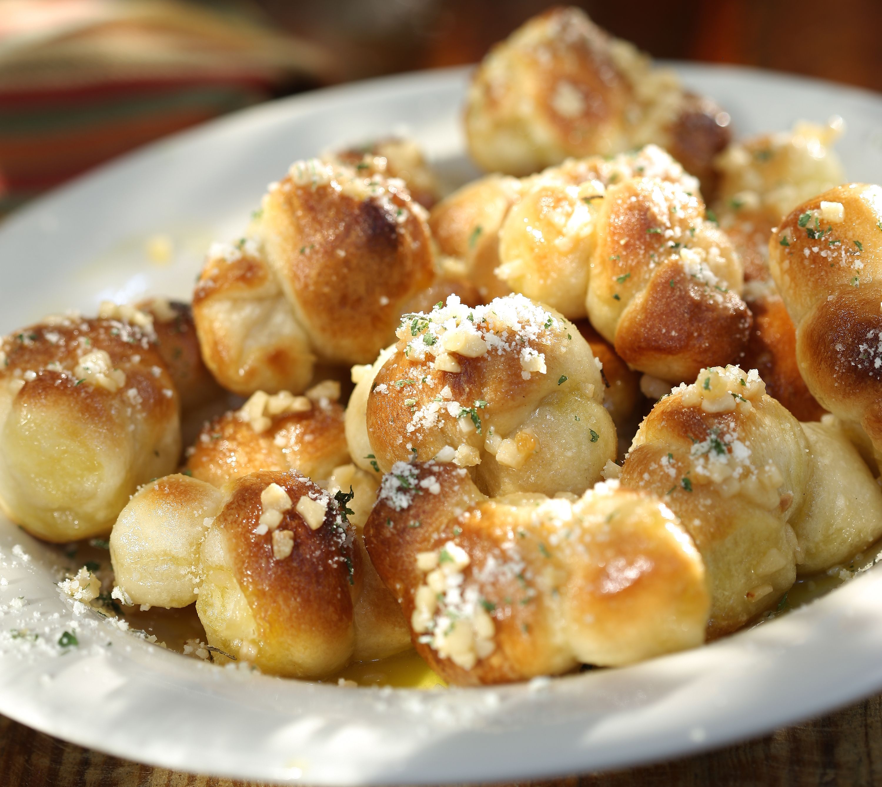 MINI GARLIC KNOTS - Our pizza dough rolled and tied into knots, baked, then smothered in melted butter and fresh garlic. Served with a side of marinara.