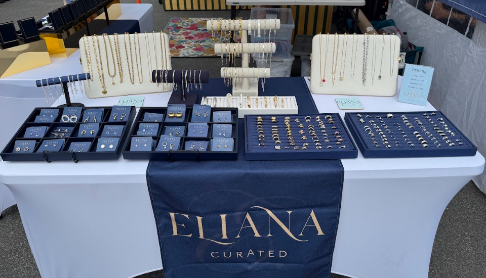 Eliana Curated presents an elegant market display featuring beautifully arranged necklaces, bracelets, earrings, and rings in gold and silver tones, offering stylish pieces for every occasion.