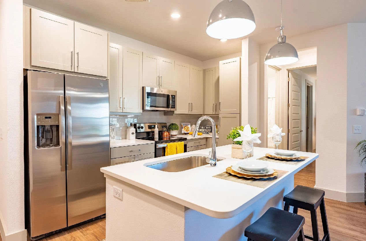 Full kitchen at The Drake Apartments in Midland, TX with white shaker cabinets, stainless steel appl 