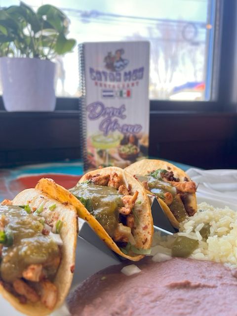 Three grilled chicken tacos topped with salsa verde and served with Mexican rice and refried beans at Catramex Restaurant.