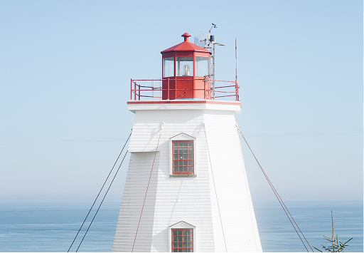 A photo of the top of a white and red lighthouse.