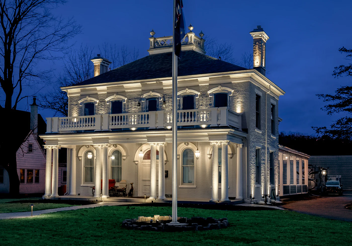 Elegant warm architectural lighting highlighting columns, rooflines, and detailed exterior features of a large residence.