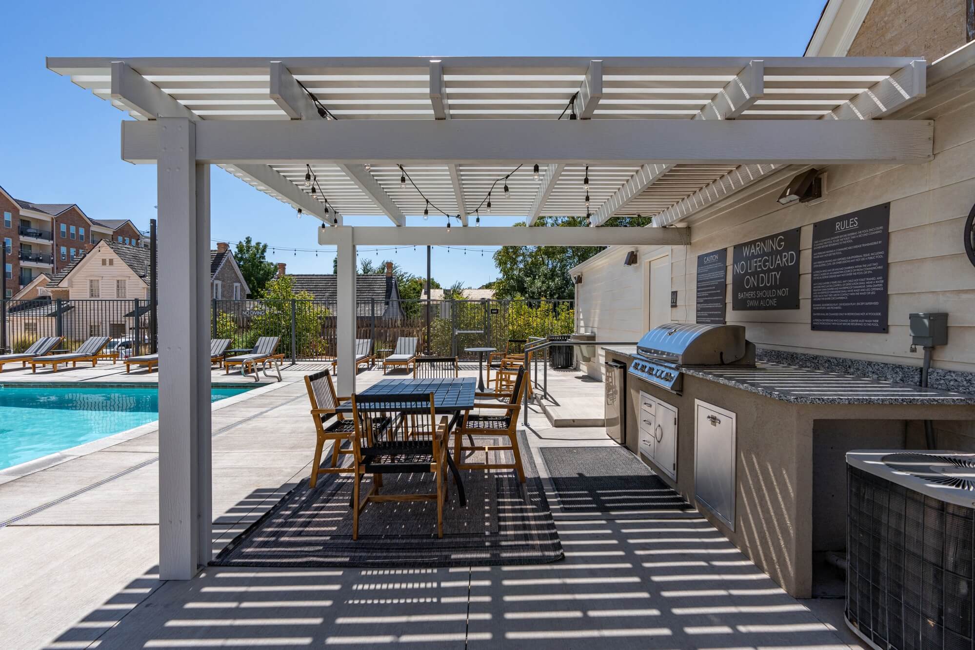 a patio with a grill and a table with chairs and a pool