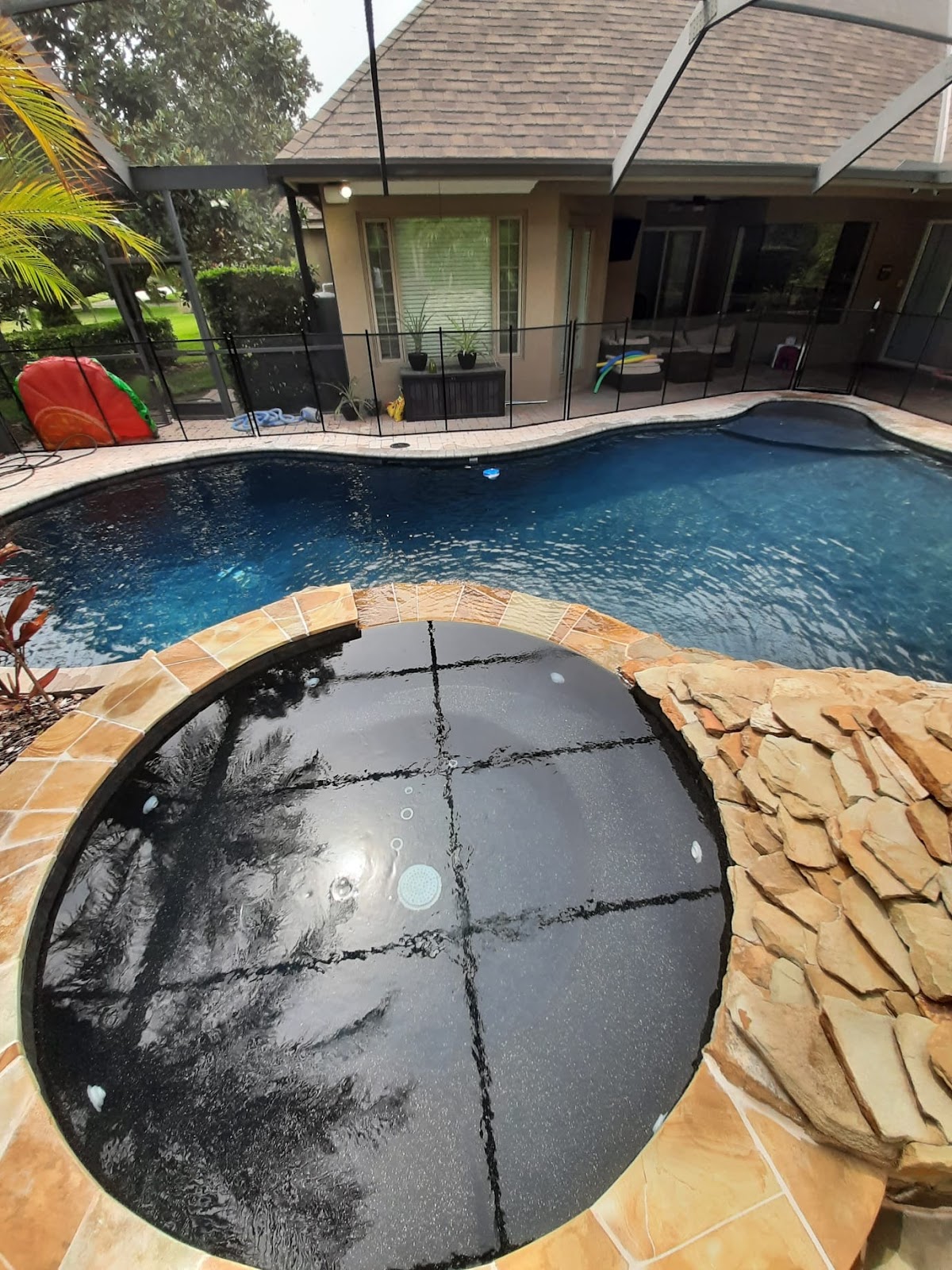 Residential swimming pool undergoing renovation or resurfacing, with pool equipment and construction materials visible around the deck.