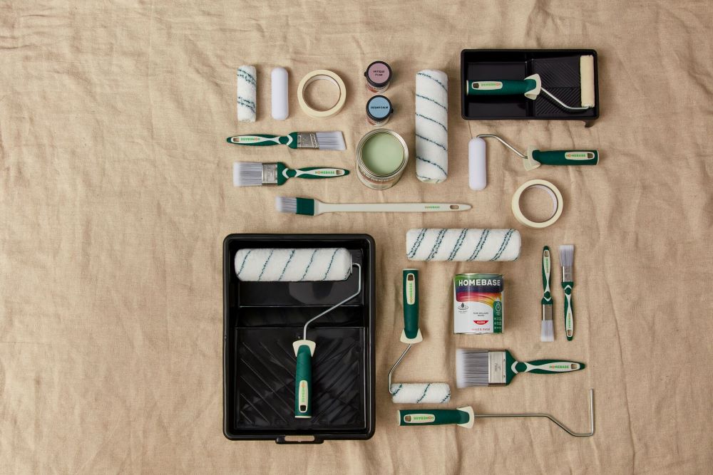 A selection of paint tools and accessories on a dust sheet, including brushes and rollers.