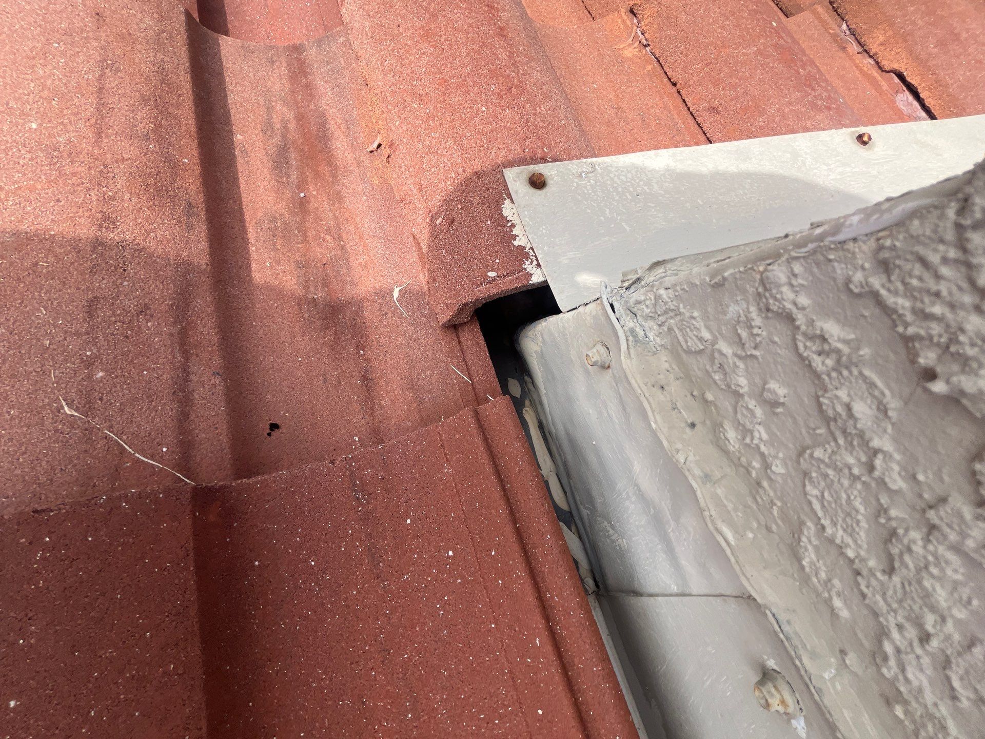 Close-up of roof flashing where the tile roof meets a wall or roof transition, showing an important  