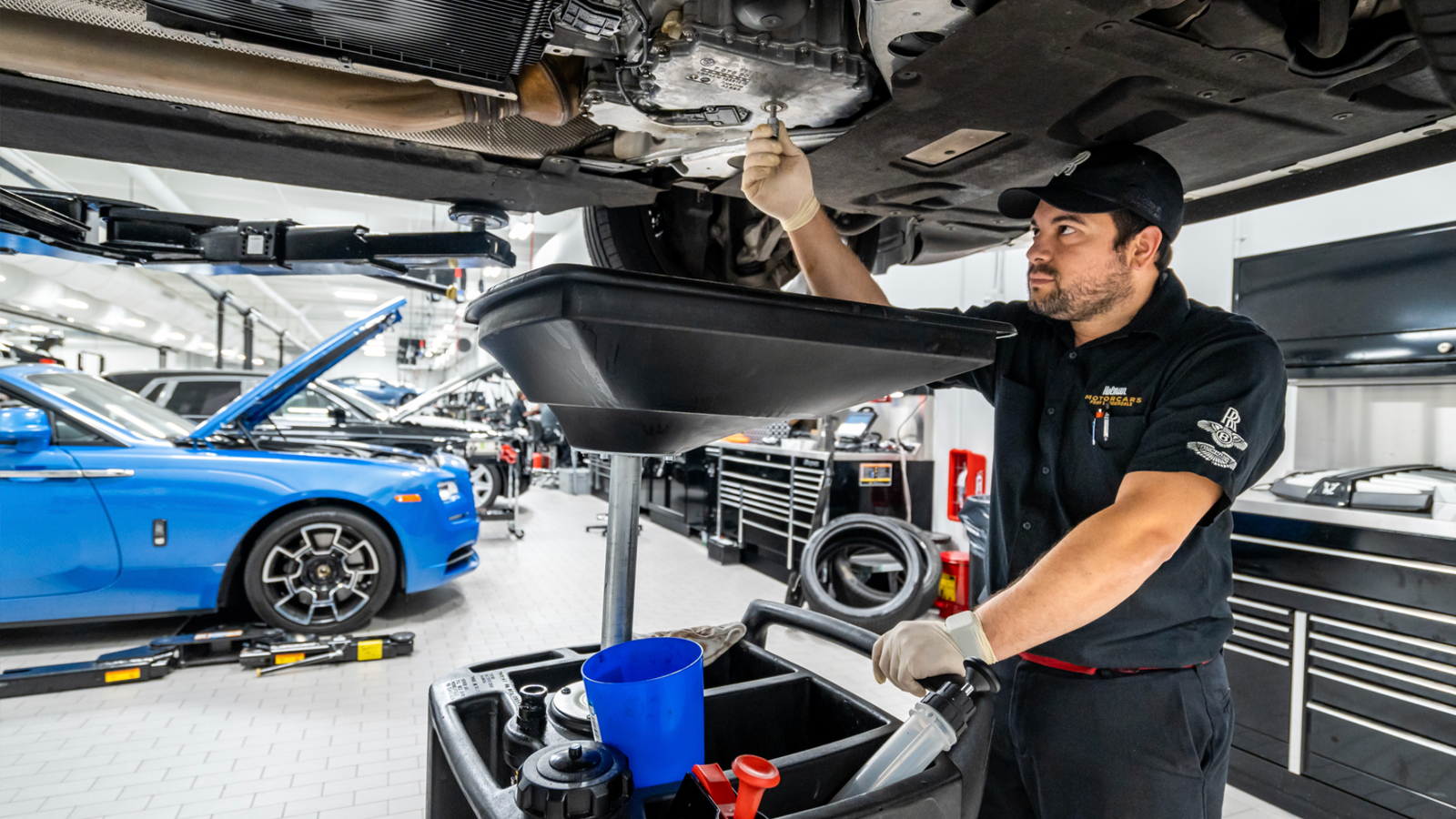 A service technician working under a vehicle on a lift