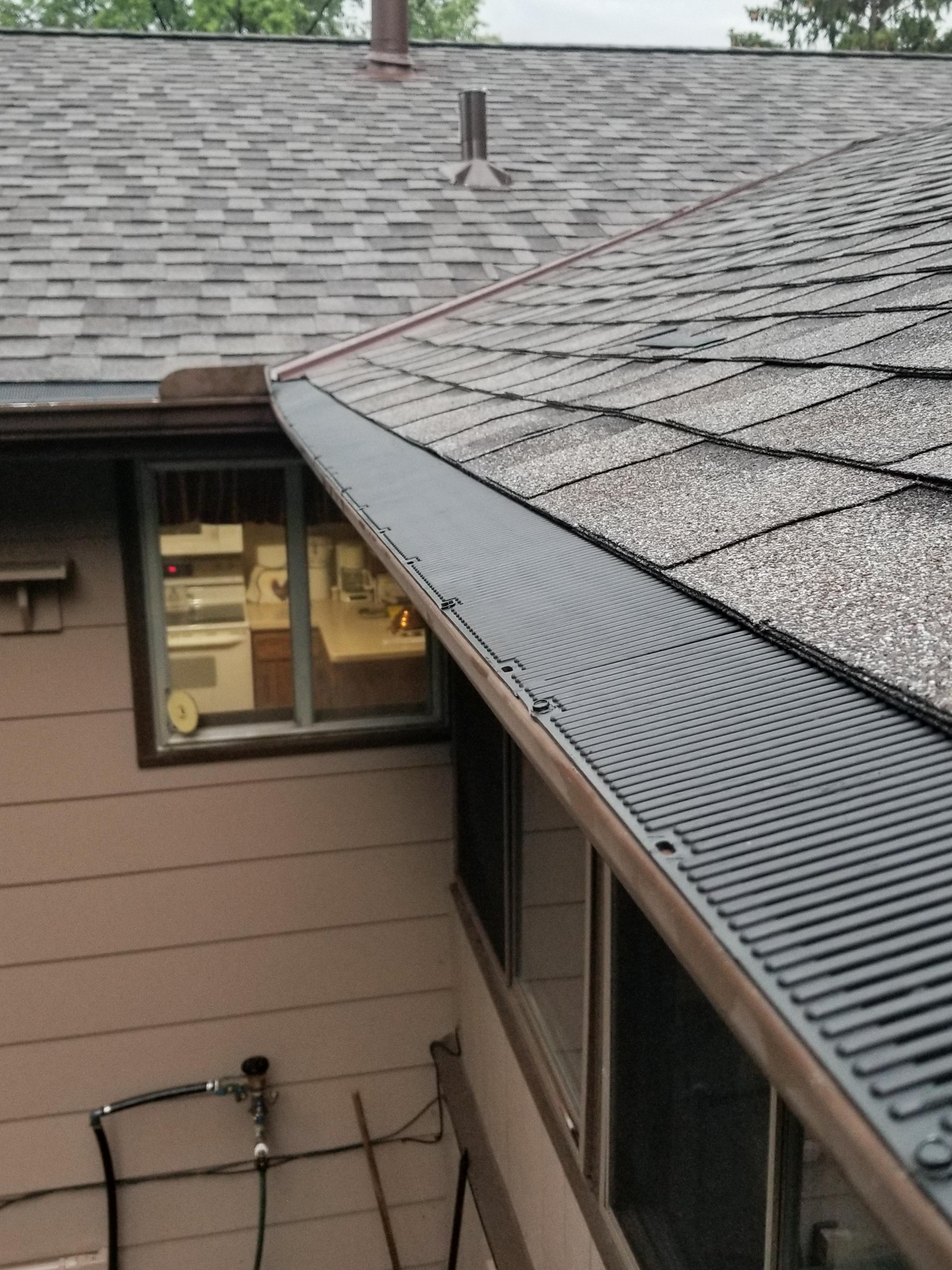 Black ribbed gutter guard on a brown seamless gutter installed by Ultimate Gutter Solutions.