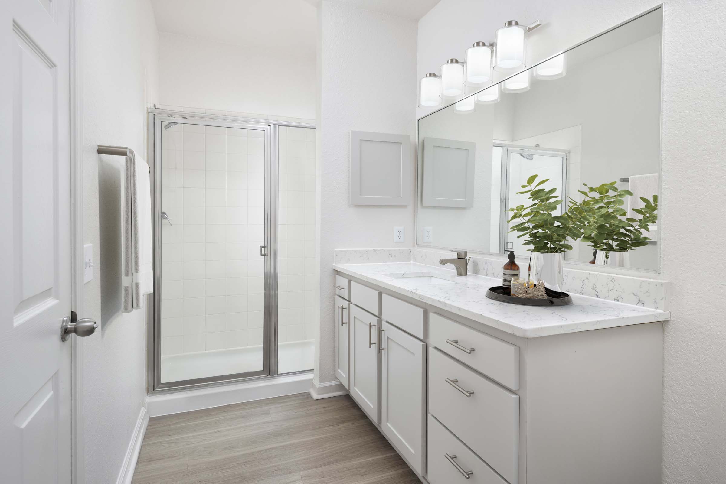 apartment home primary bathroom with white quartz countertops and walk-in shower at camden visconti