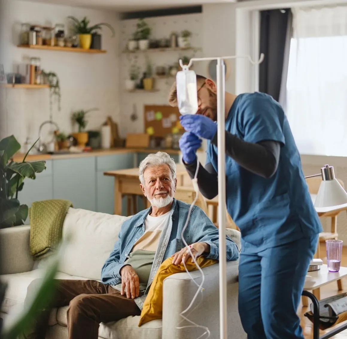 Nurse Helping Senior at Home
A skilled home health nurse administers IV care to an elderly gentleman in the comfort of his own living room. CareGivers of America brings professional care directly to your door &mdash; so your loved one can heal and thrive right where they belong: at home.