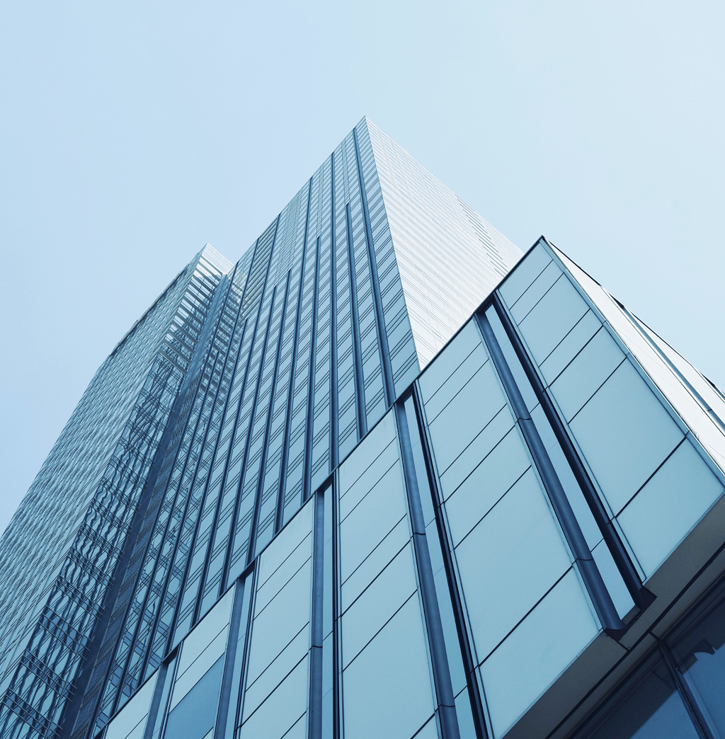 Bottom-up view of a modern, reflective skyscraper under a clear blue sky.