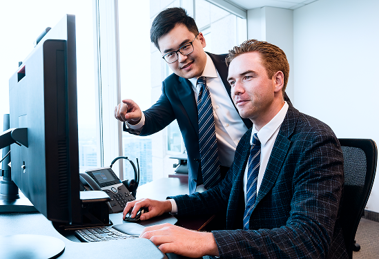 Two members of the Rae Family Wealth team looking at a monitor.
