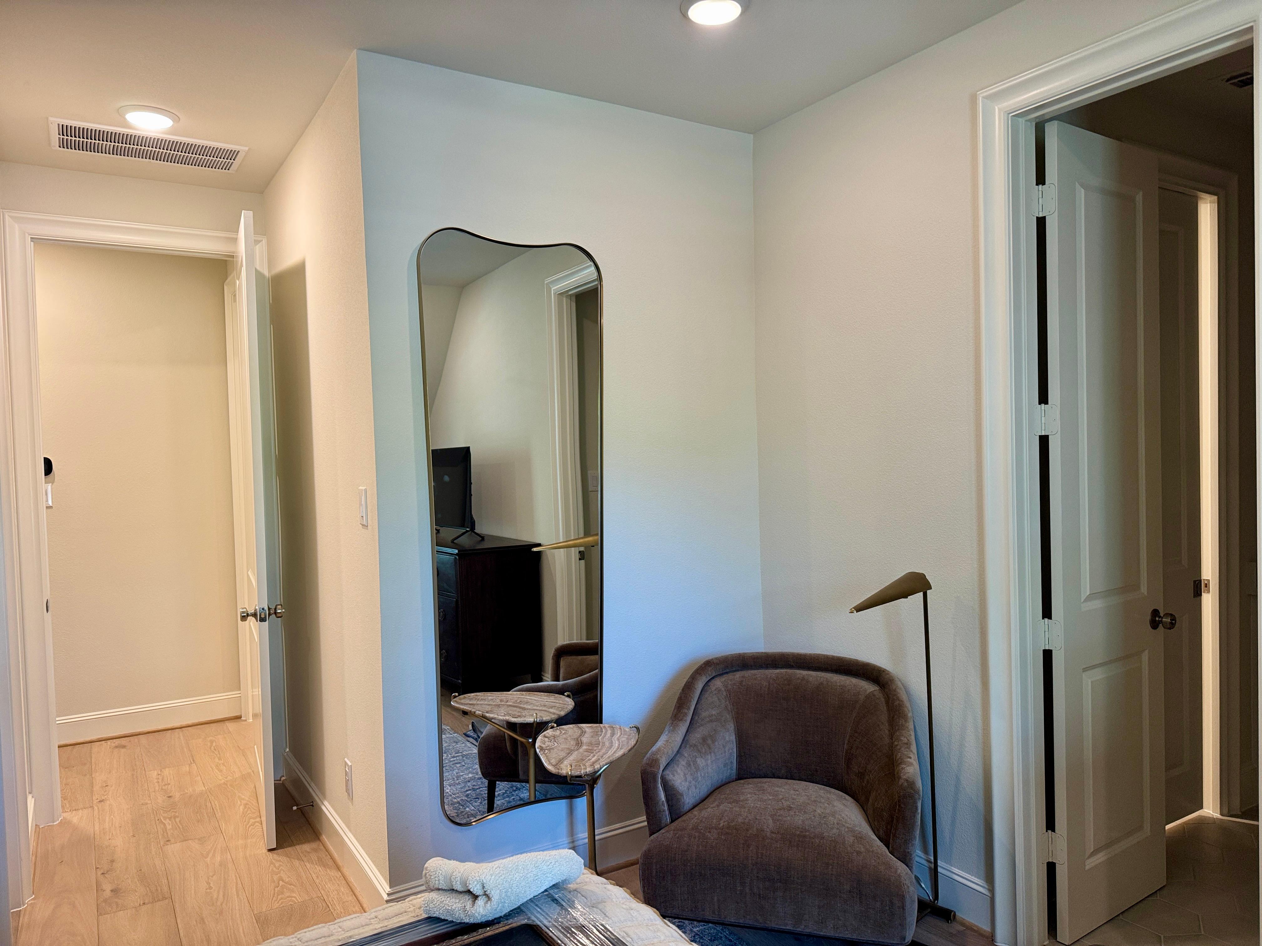 Wall-mounted full-length mirror installed in a residential bedroom sitting area in Memorial Villages Houston, Texas.