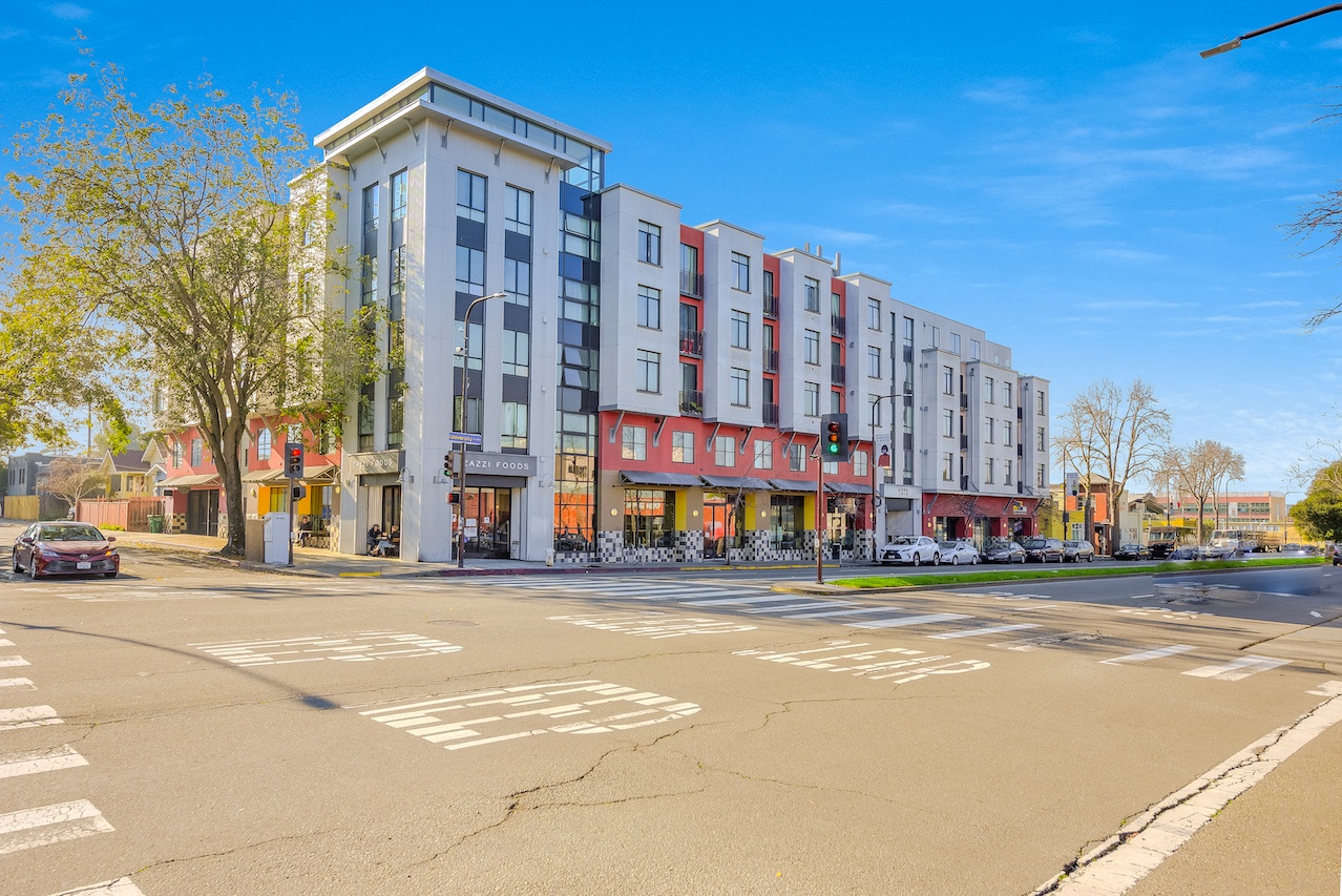 A street view of a multi-story building with a car parked in front. 