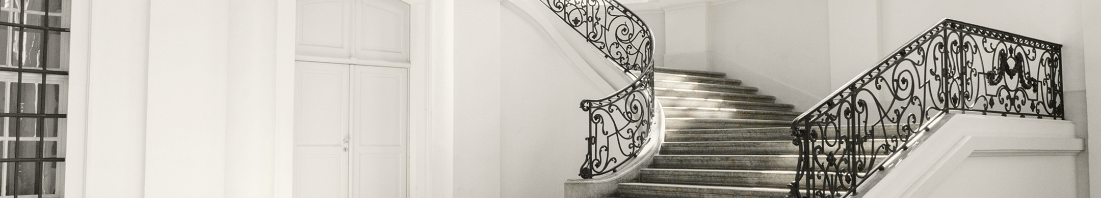 Grand staircase with ornate railings in a white entryway.