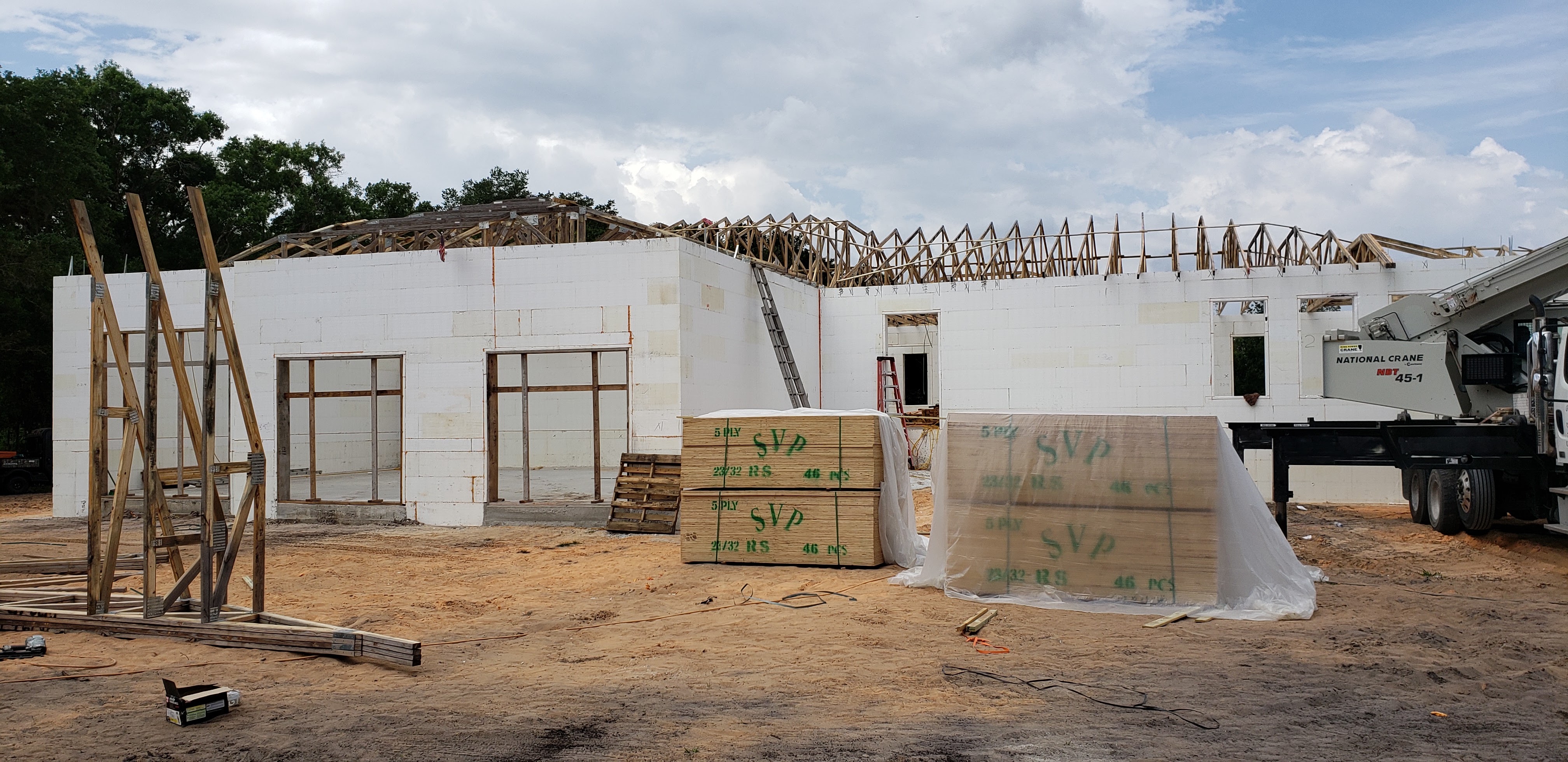 A construction site showing the unfinished framework of a building, with walls made of white insulat 