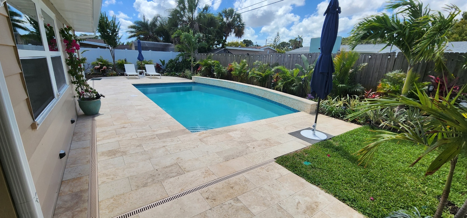 Modern rectangular backyard swimming pool with a clean deck, landscaped surroundings, and comfortable outdoor living space.