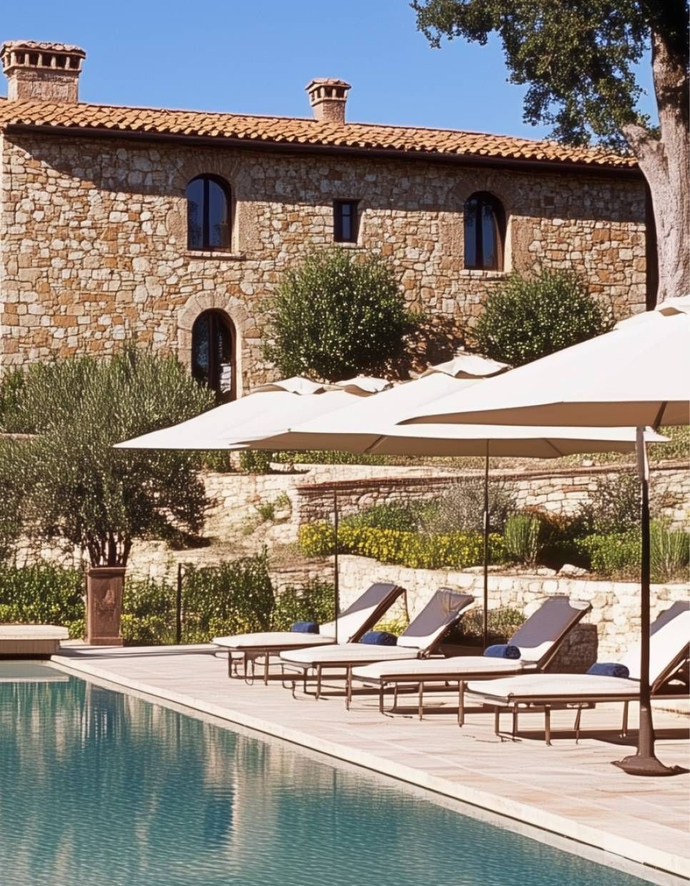 Close view of luxury villa pool area with sun loungers, umbrellas, stone architecture, and landscaped surroundings, highlighting premium outdoor living and resort-style residential construction quality.