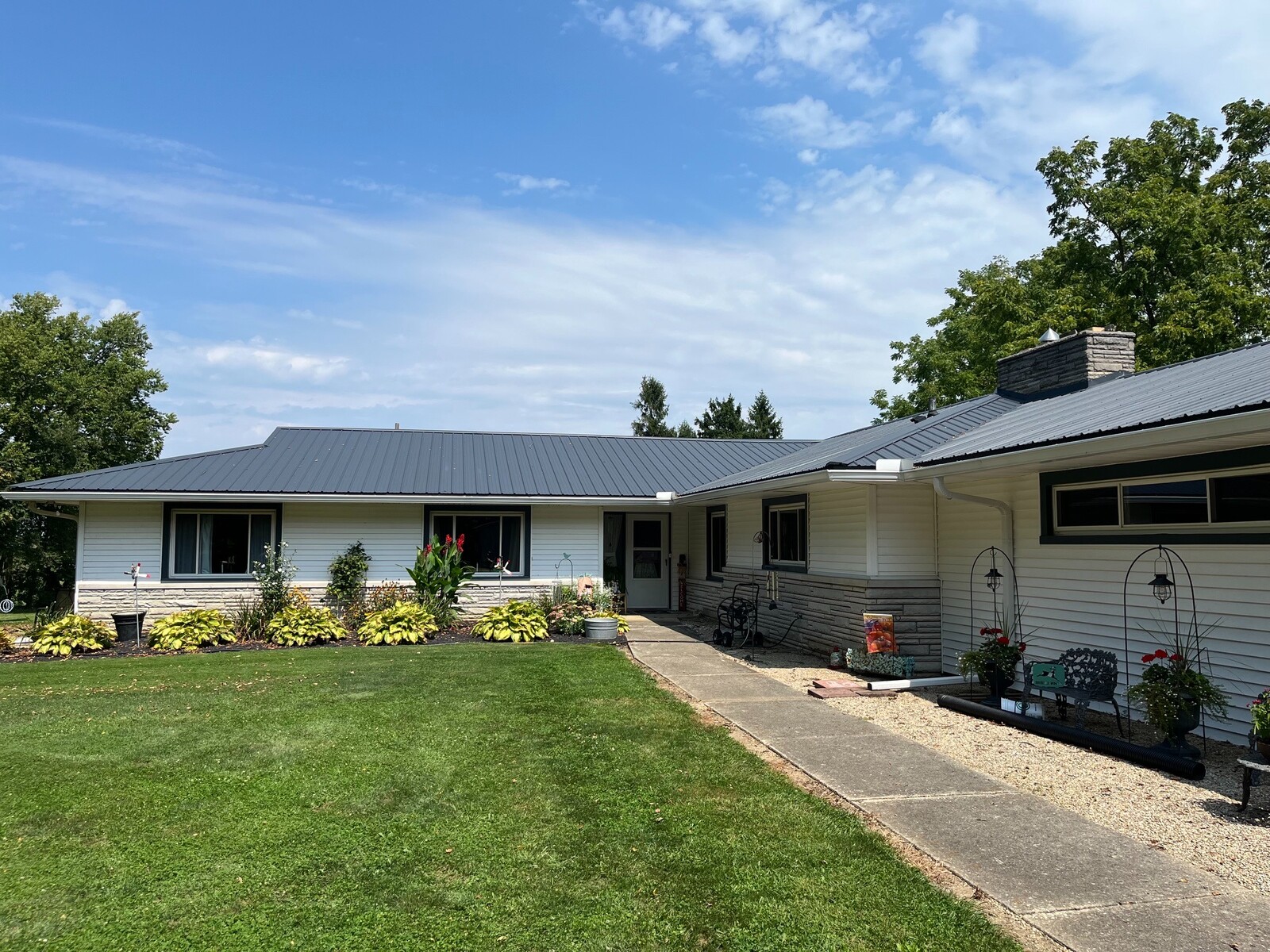 Standing seam metal roof installation shown from the landscaped courtyard of a residential property.
