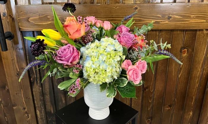 Fresh garden arrangement featuring tulips, hydrangeas, roses, spray roses, scabiosa scoops, veronica and mixed greenery.