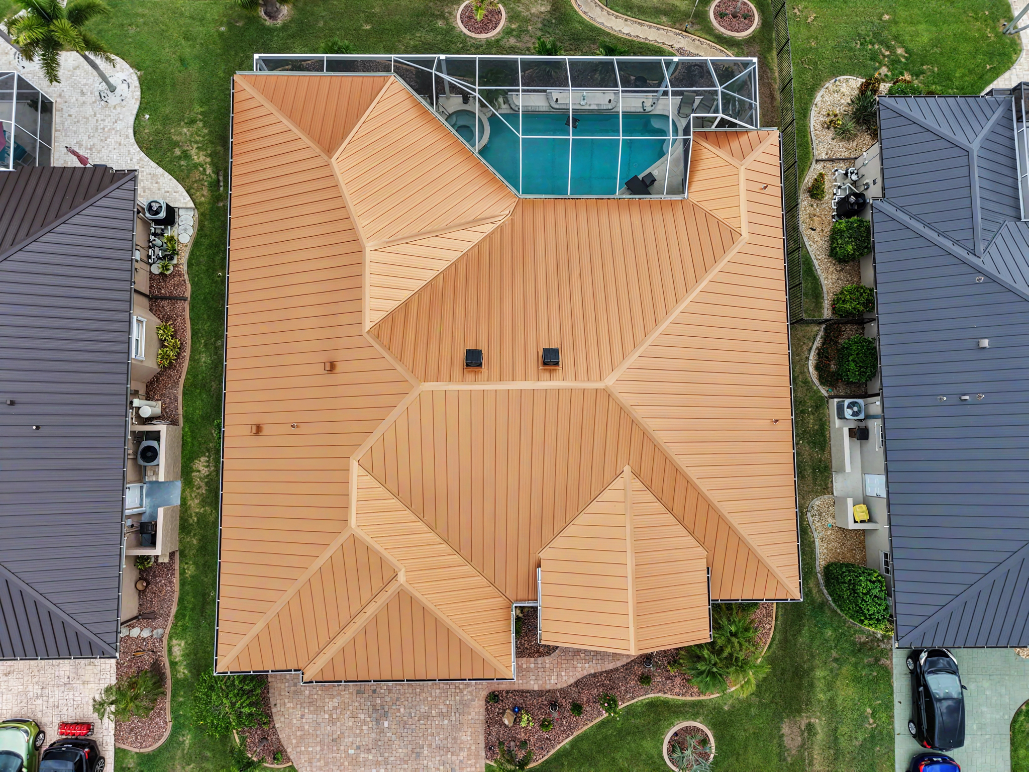 Top-down drone view showing the detailed layout, ridges, valleys, and roof penetrations of a copper- 