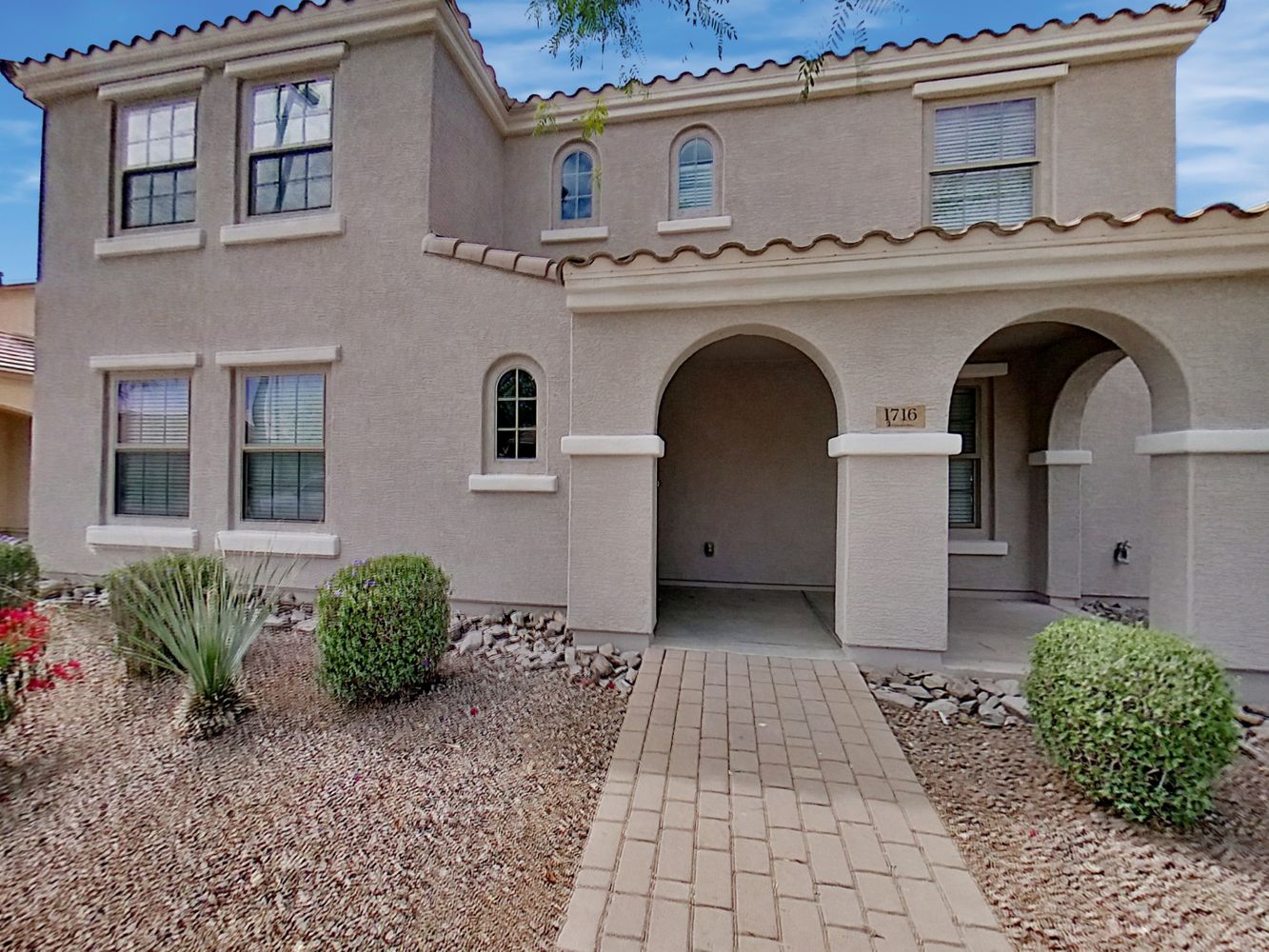 Beautiful two-story home with covered patio and stone walkway at Invitation Homes Phoenix.