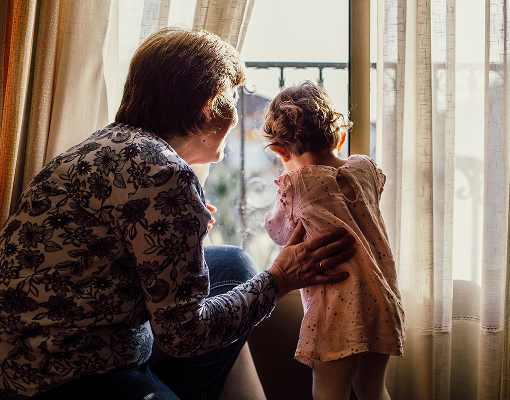 A grandmother and her grandchild looking out the window.